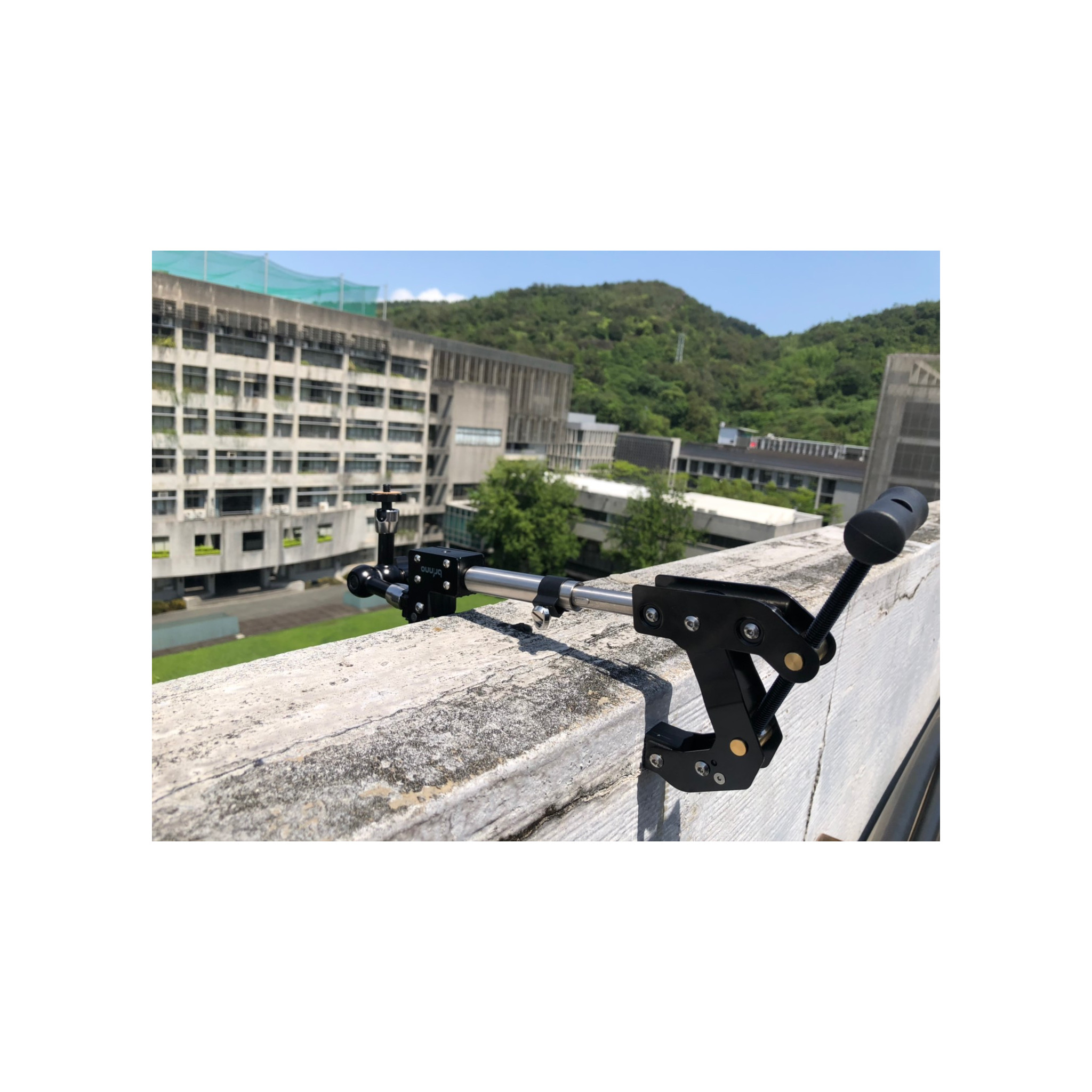Un supporto per fotocamera nero su un muro esterno, con edifici sullo sfondo.