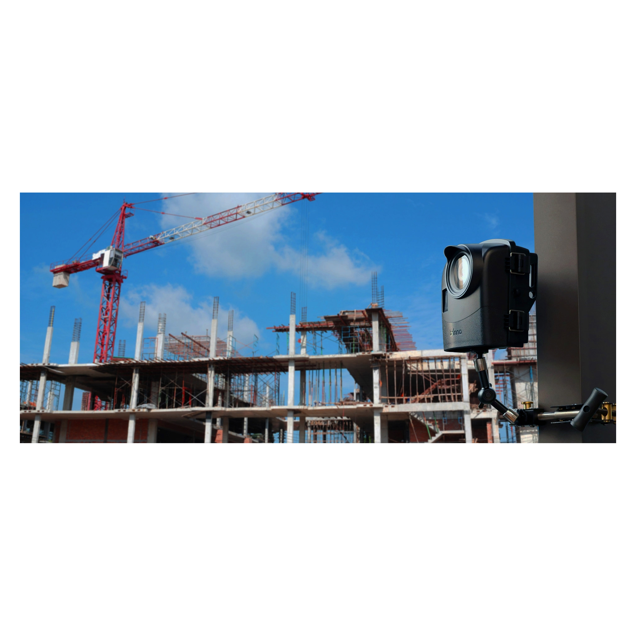 Telecamera nera montata su un palo di metallo in un cantiere con cielo blu e gru.
