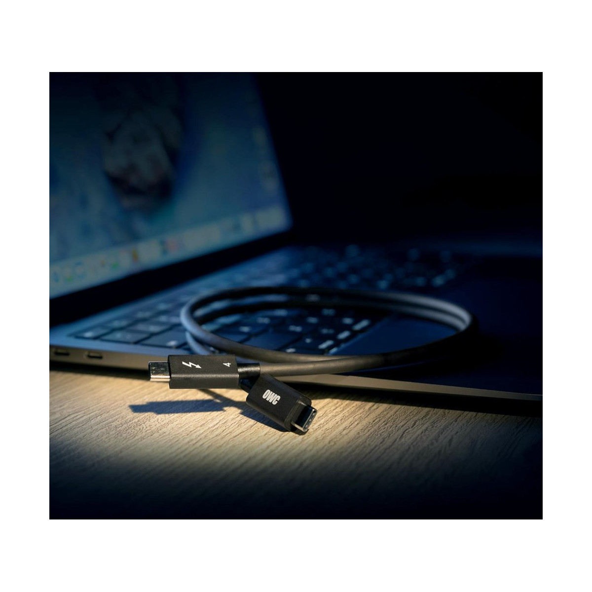 Een laptop met een oplaadkabel aangesloten. De kabel is zwart met een bliksemsymbool op de connector.