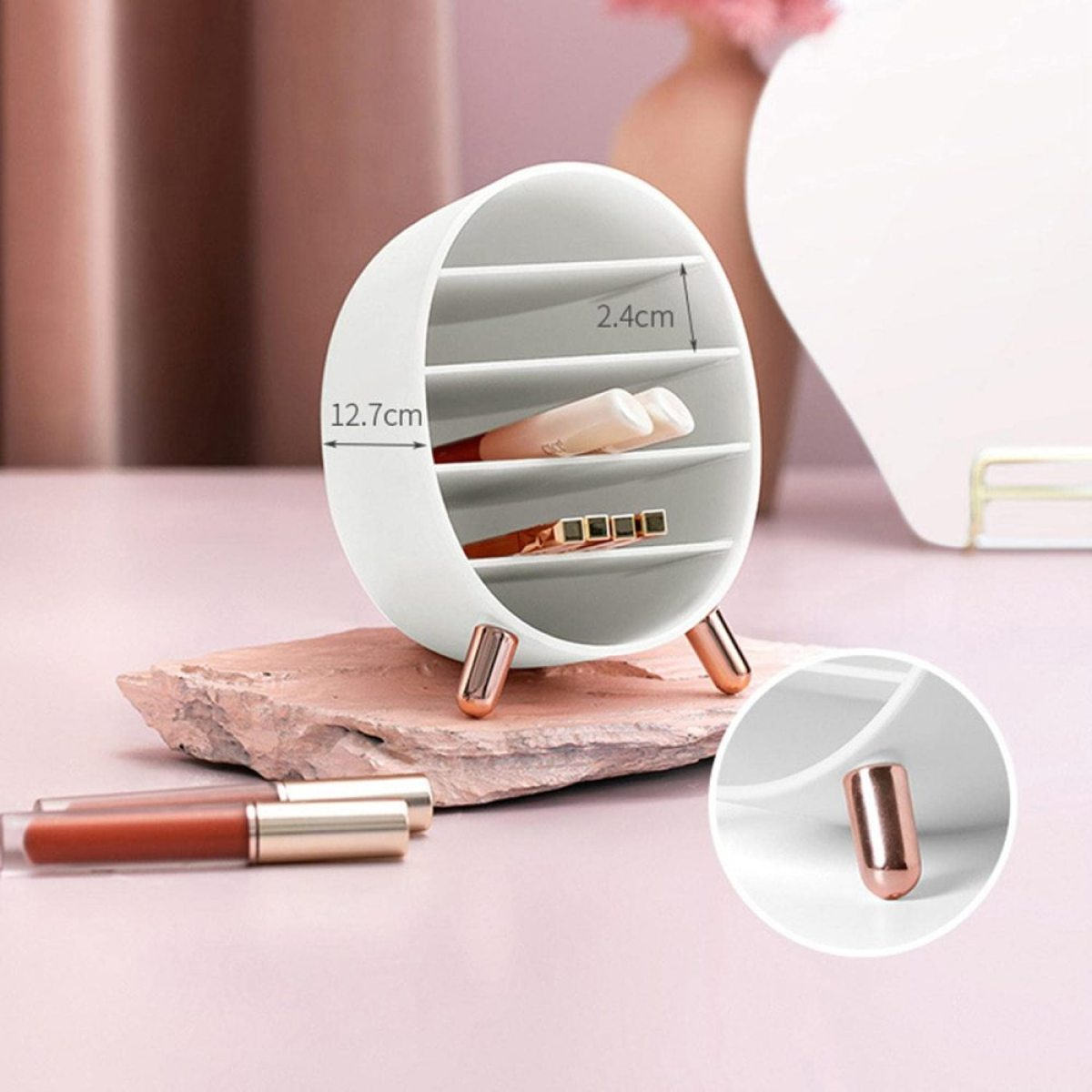 Weißer Kosmetik-Organizer mit mehreren Fächern. Steht auf rosa Oberfläche mit Lippenstiften.