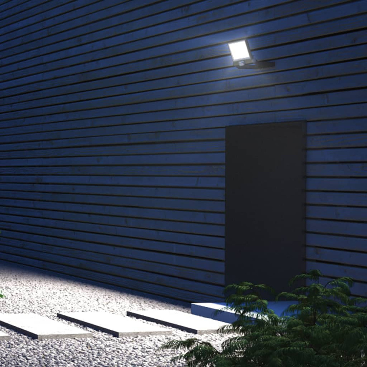 Außenszene bei Nacht. Wand, Licht und Stufen beleuchtet. Grüner Busch in der Ecke.