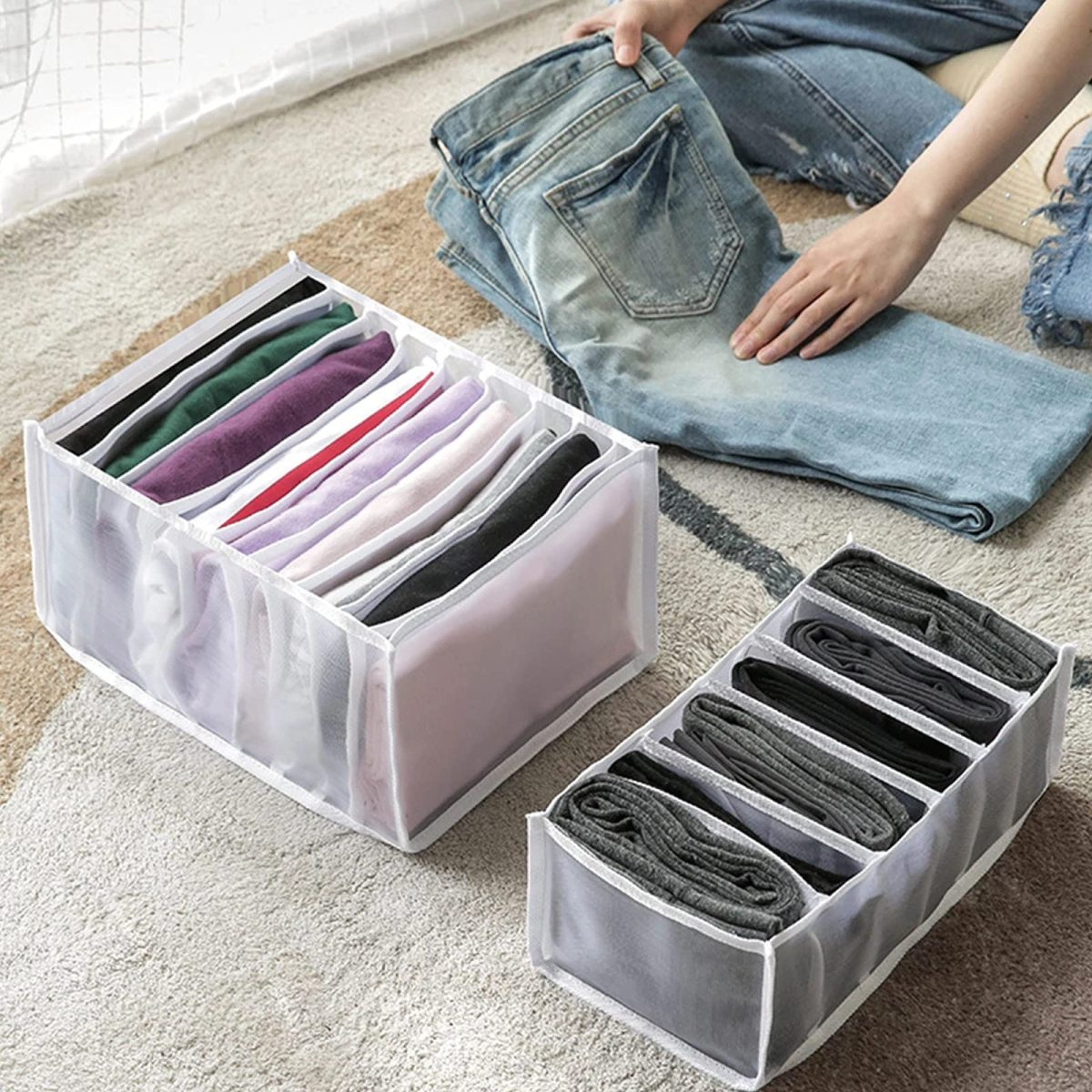 Zwei Organizer mit Kleidung gefüllt. Einer hält gefaltete Hemden, der andere Socken und Hosen.