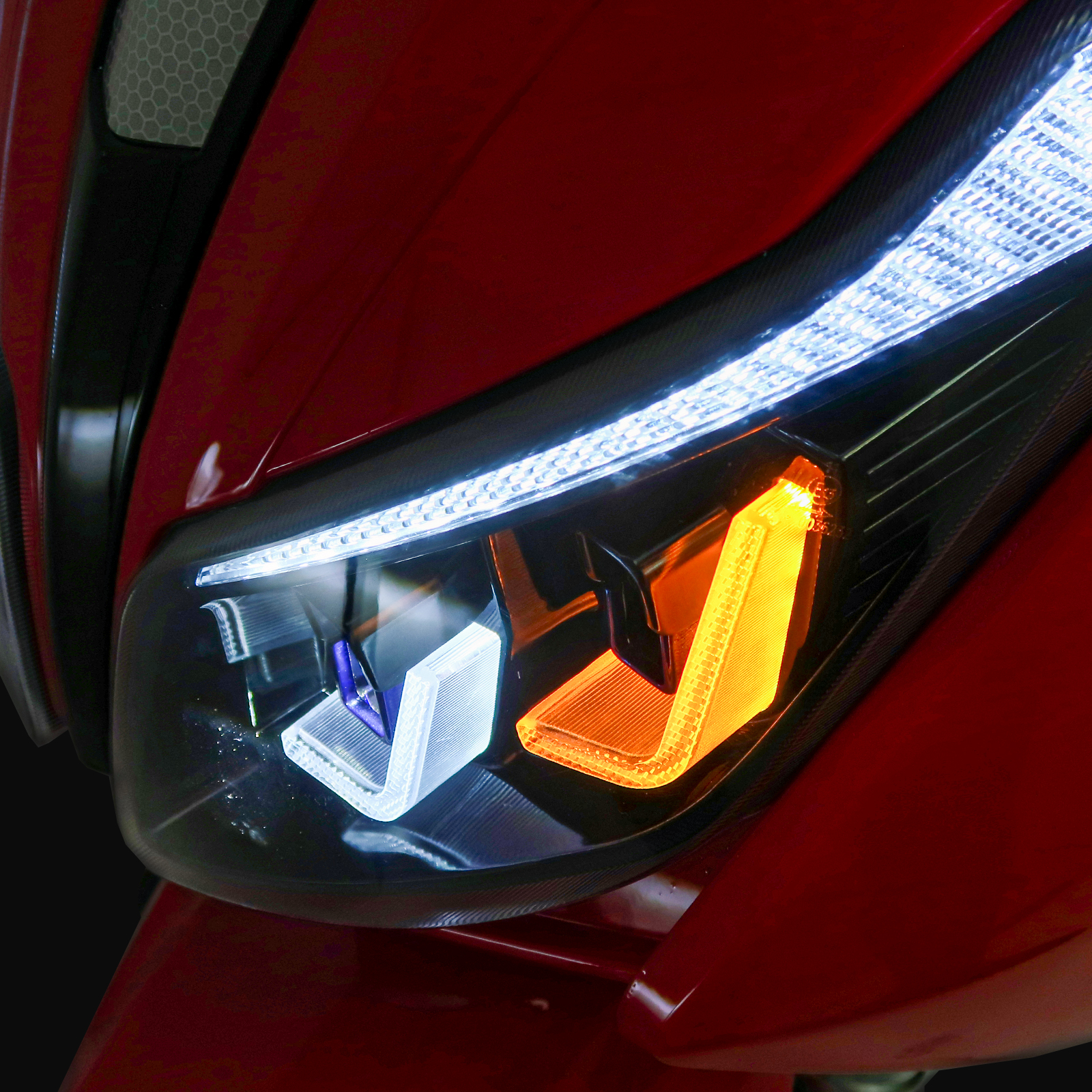 Autoscheinwerfer mit weißem LED-Streifen und orangefarbenem Blinker und schwarzem Hintergrund.
