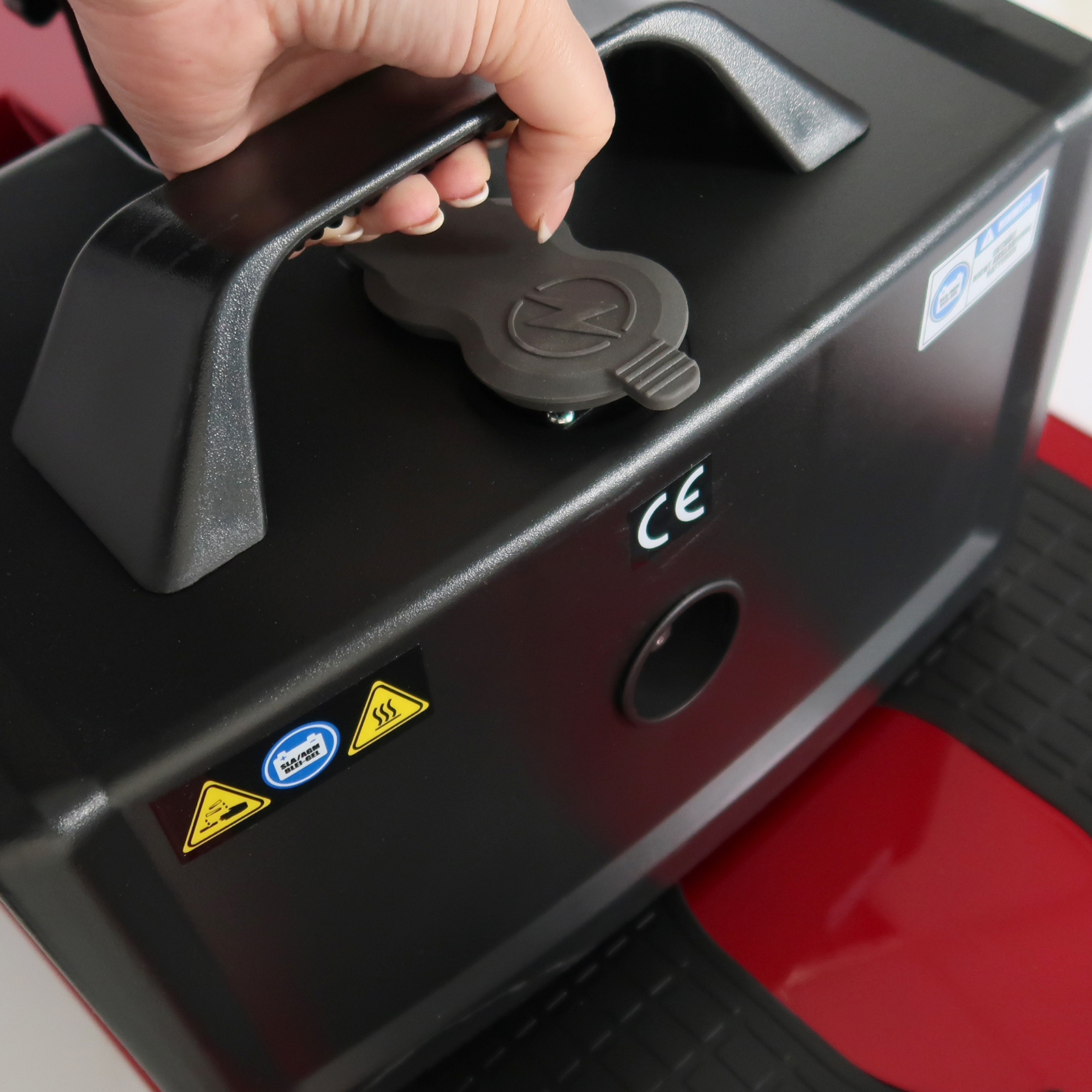 Eine Hand, die eine schwarz-rote Maschine mit CE-Kennzeichnung öffnet.