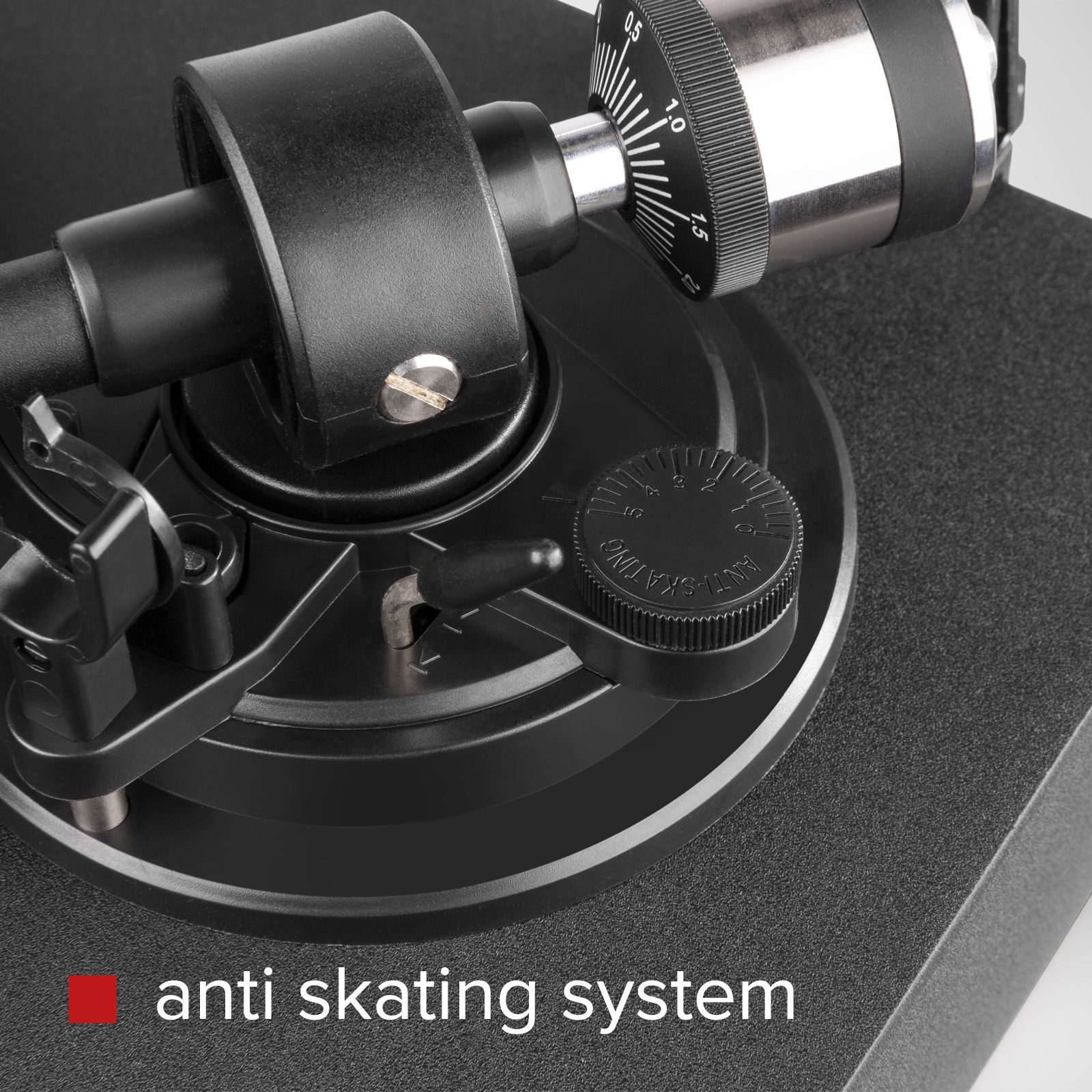 Primer plano del brazo fonocaptor de un tocadiscos negro. El sistema anti-patinaje está etiquetado con texto rojo.