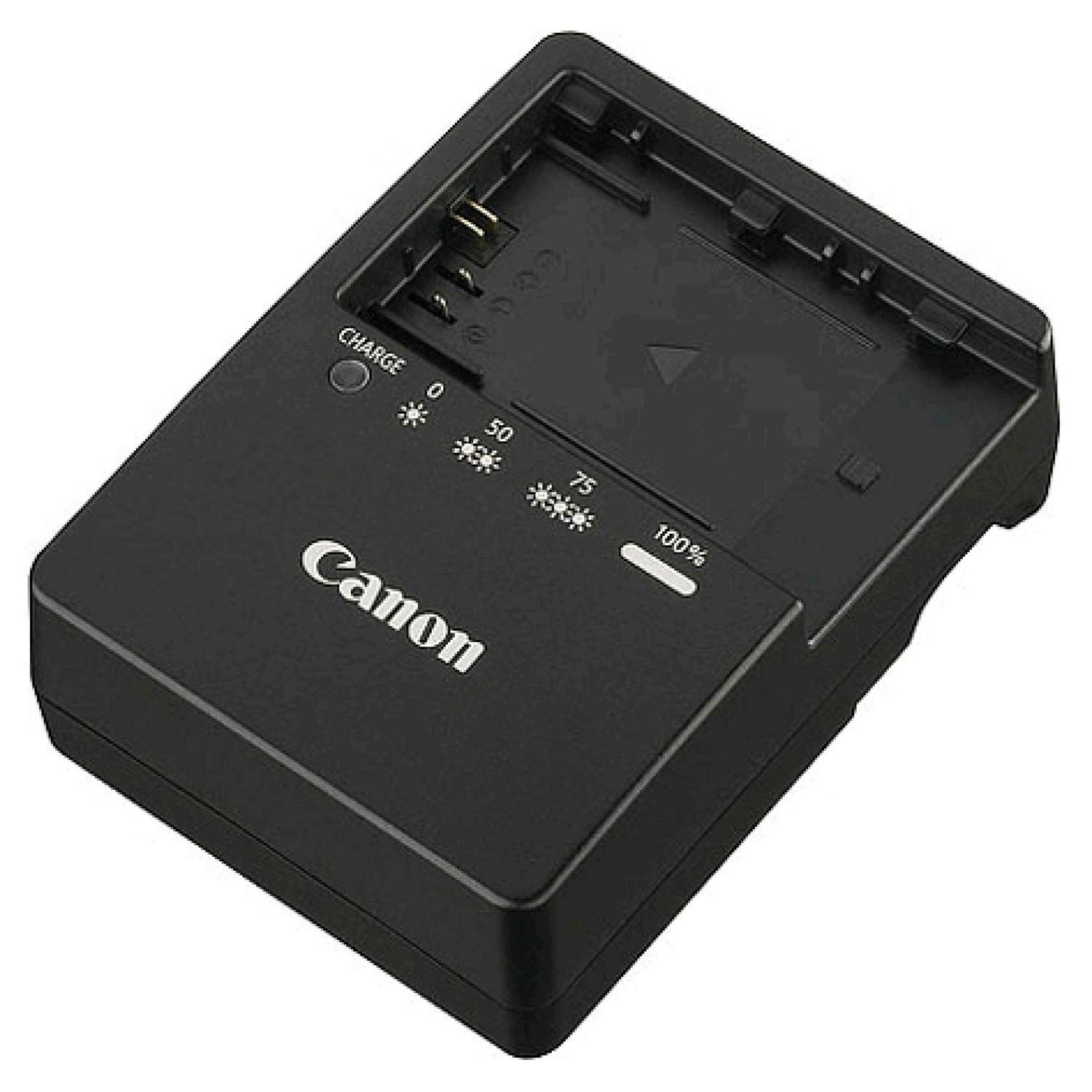 Un cargador de batería de cámara Canon negro. Tiene un indicador de carga.