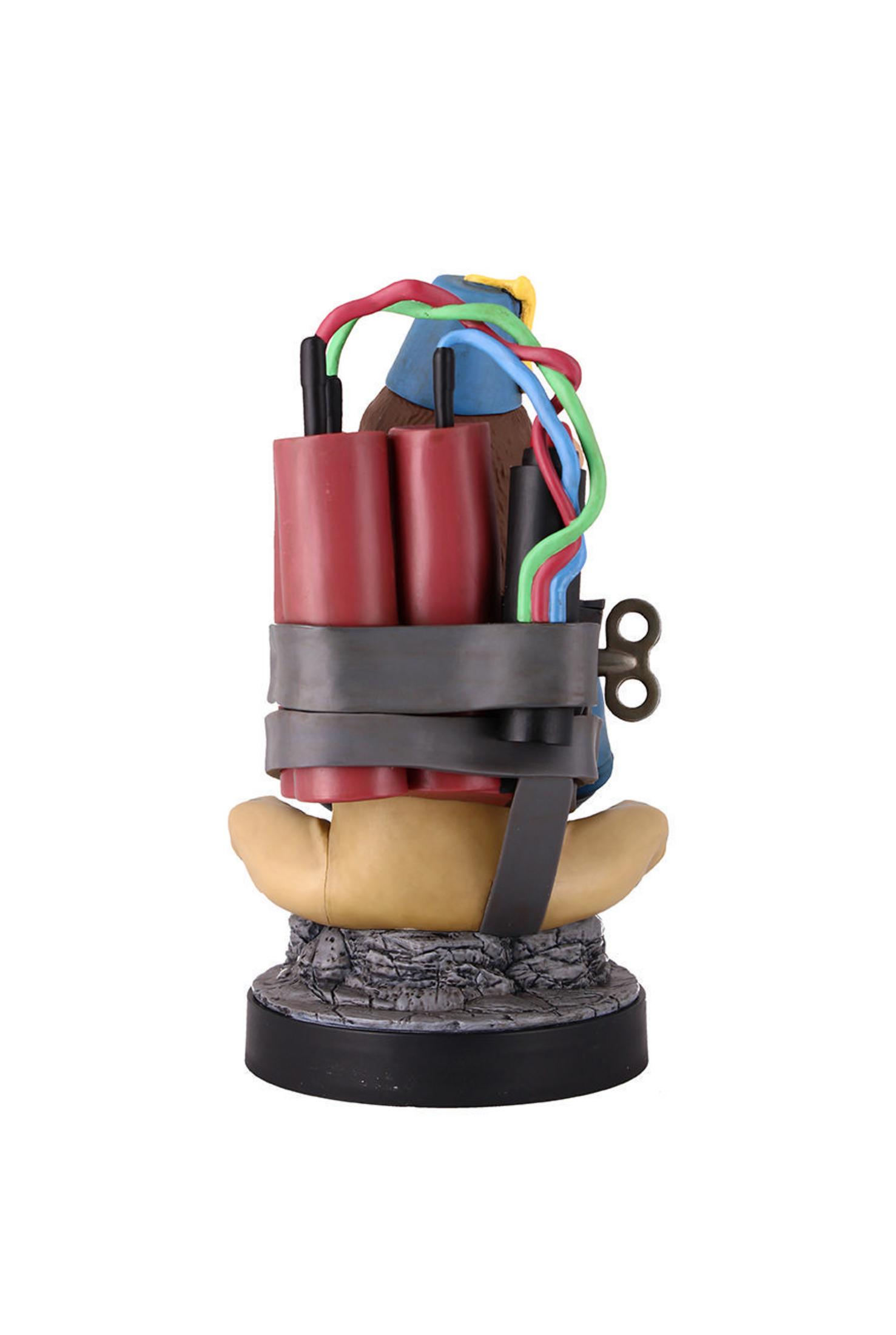 Eine Spielzeugbombe mit roten Dynamitstangen, Drähten und einem Aufziehmechanismus auf einem Steinsockel.