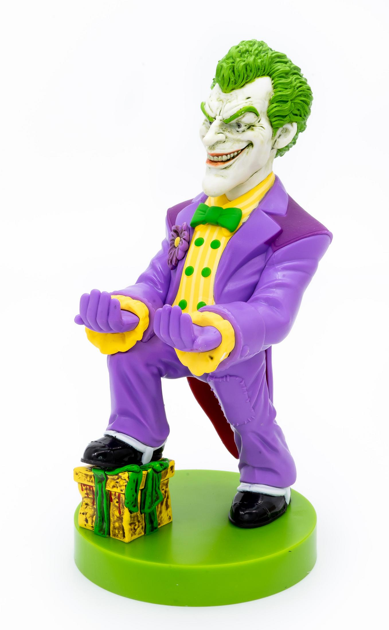 Figura del Joker in abito viola, capelli verdi, in piedi su un pacco regalo. Base verde.