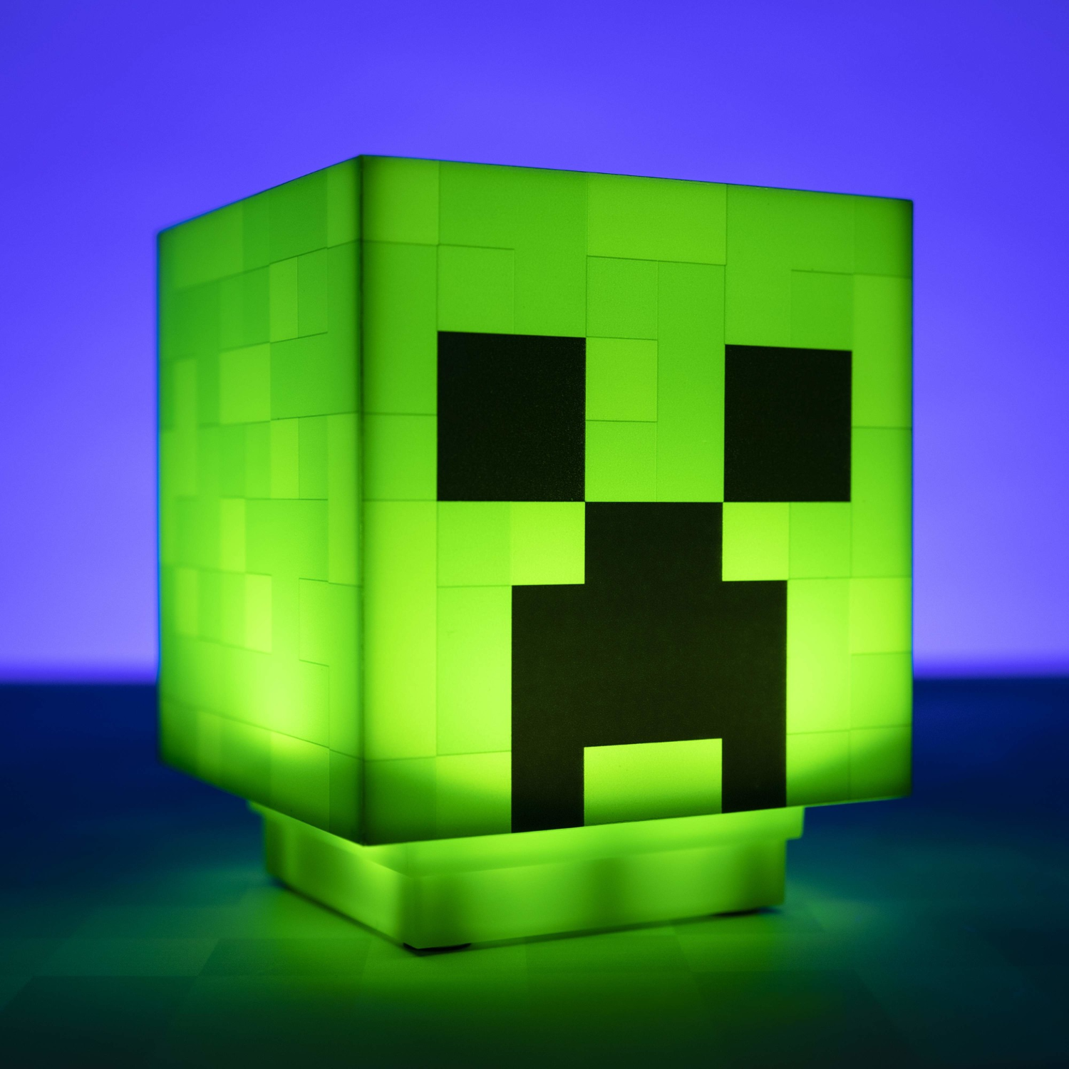 Zielona lampa Creeper z Minecraft. Czarne oczy i usta. Podświetlona. Niebieskie i zielone tło.