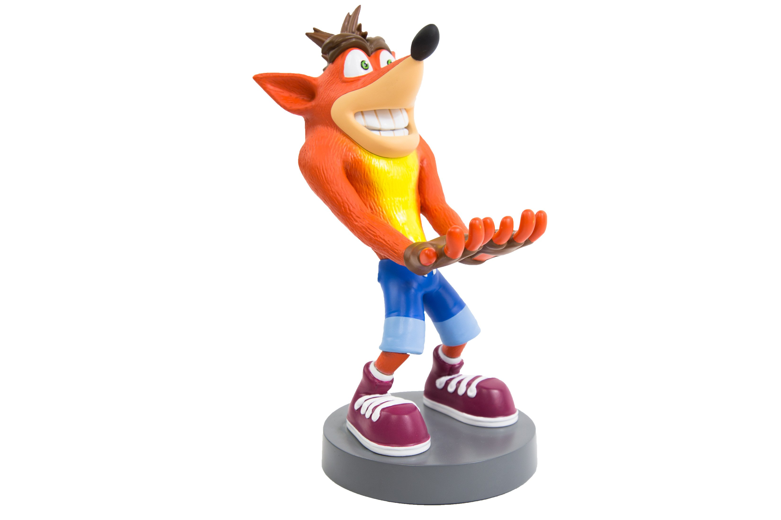 Una statuetta di Crash Bandicoot, arancione e giallo, con le braccia tese, su una base grigia.