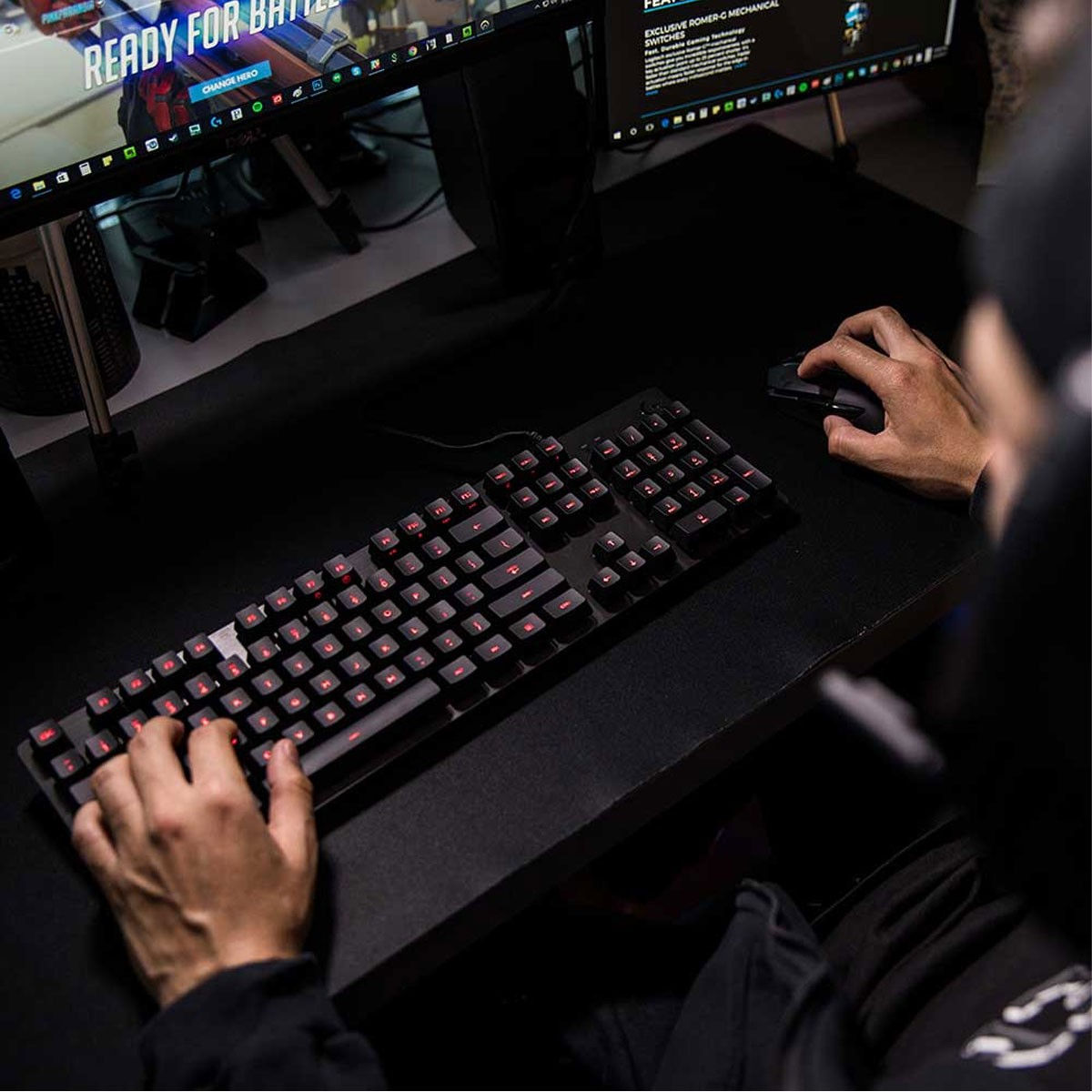 Hände benutzen Tastatur und Maus, spielen Spiel auf Monitor, dunkler Schreibtisch.