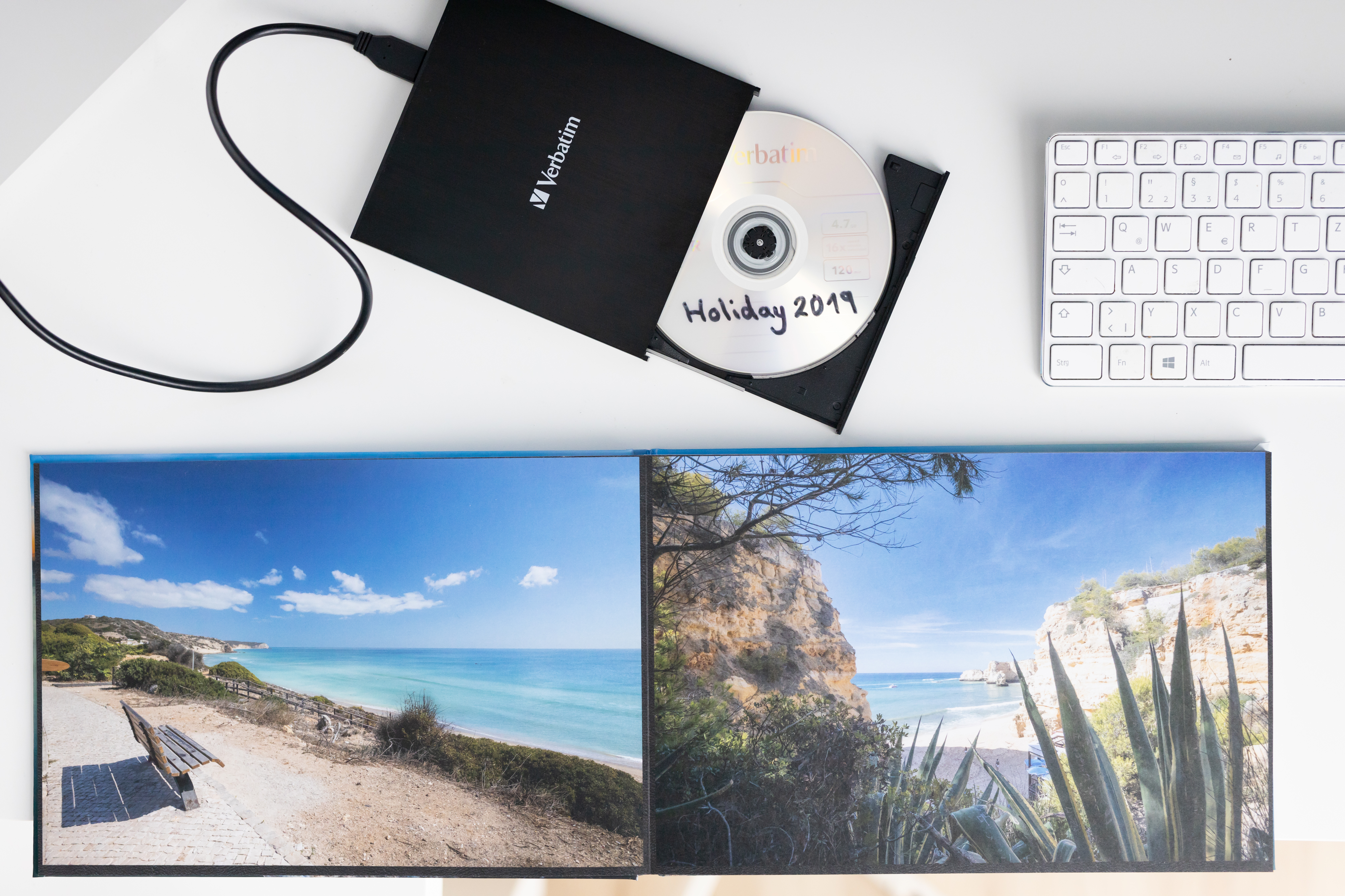 Czarny napęd CD z otwartą tacą, płyta CD z napisem 'Holiday 2019' i klawiatura.