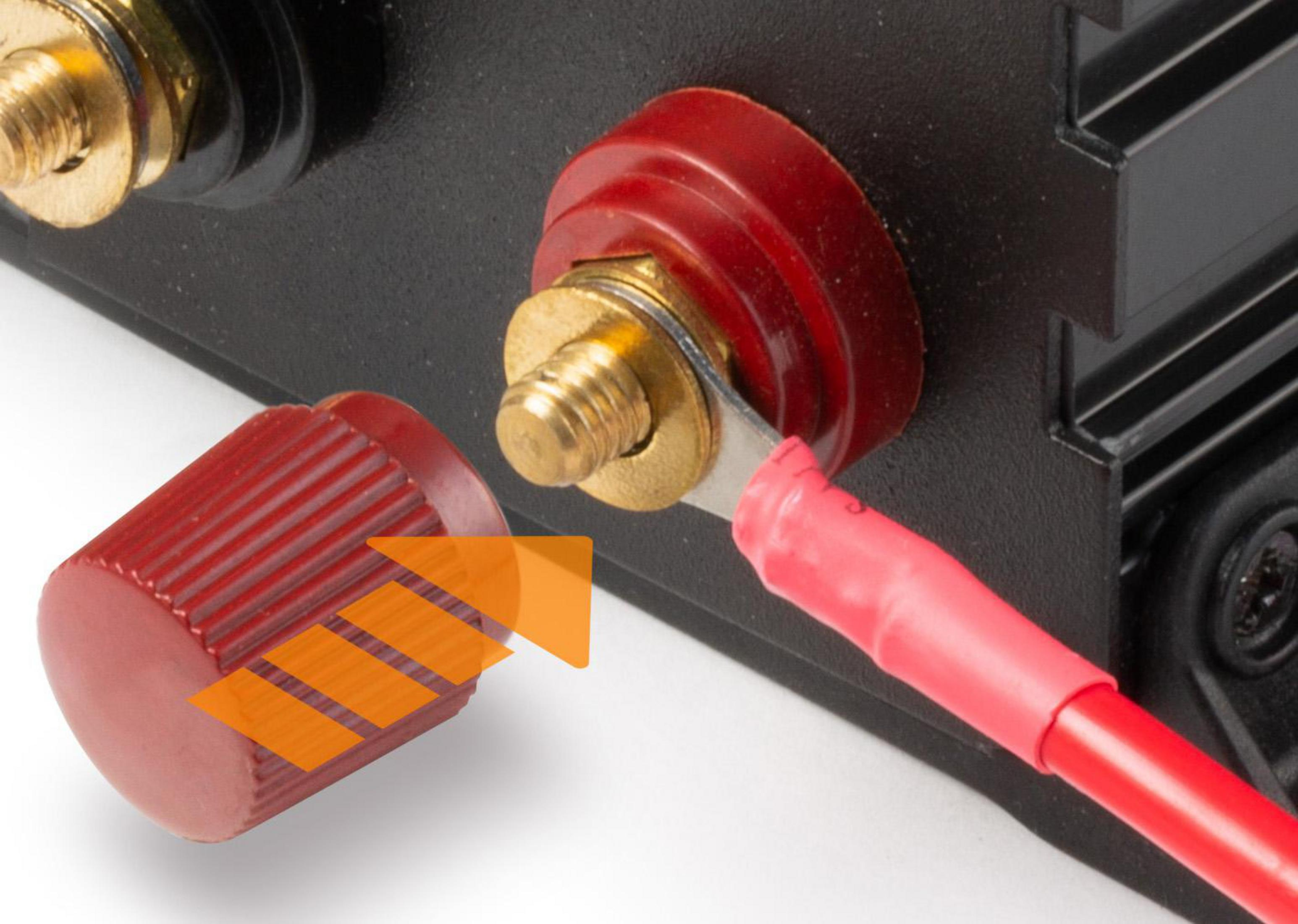 Czarne urządzenie z dołączonym czerwonym przewodem, czerwona nasadka jest odkręcana. Zbliżenie.