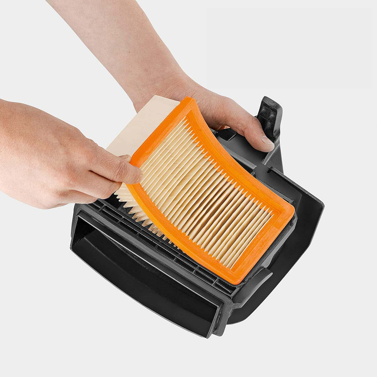 Hände halten einen orangefarbenen und beigefarbenen Luftfilter und ein schwarzes Gehäuse.