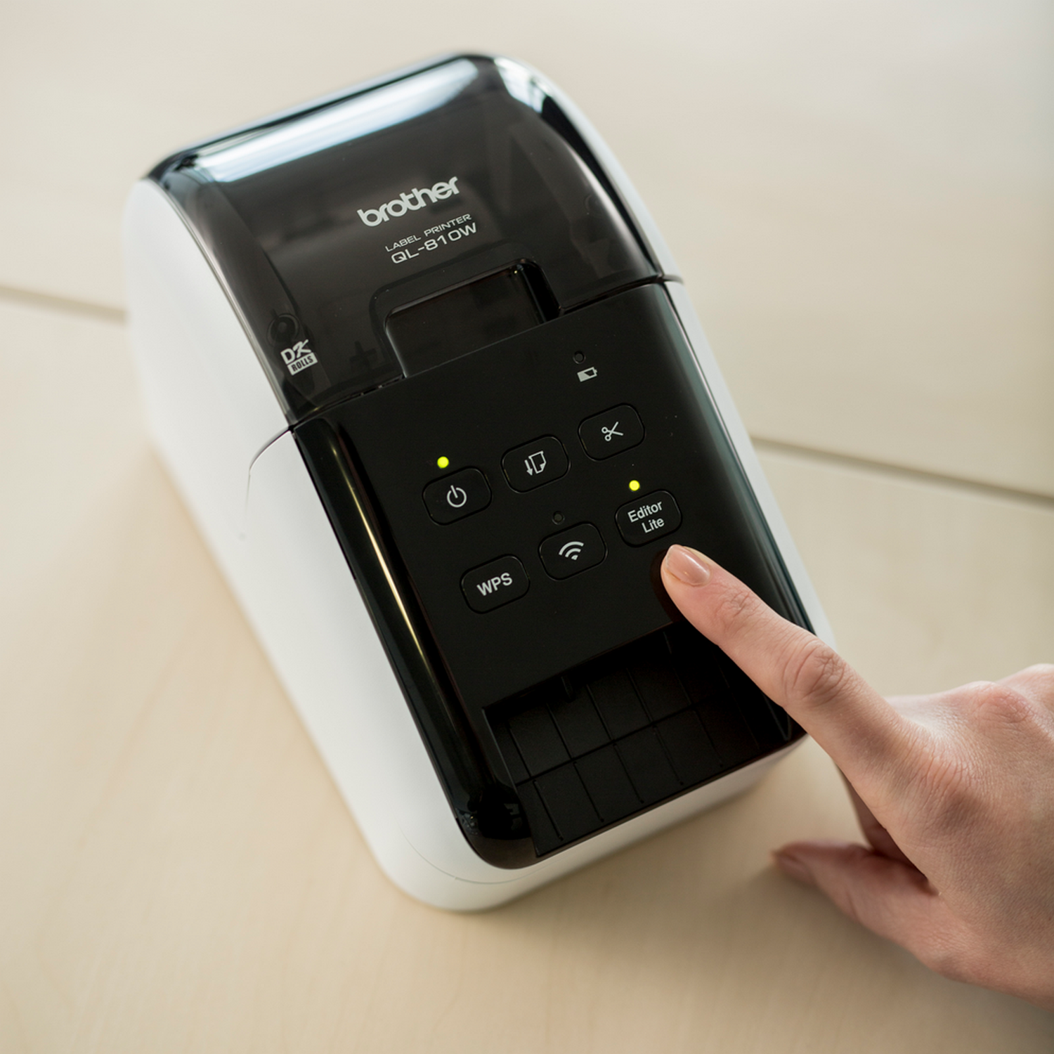 A person's finger pressing the 'Editor Lite' button on a label printer.