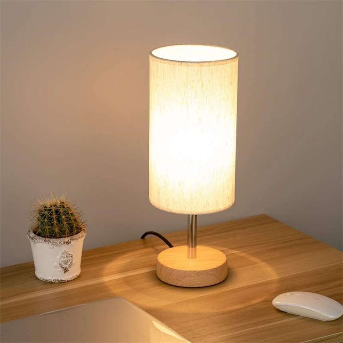 Eine Tischlampe mit beigem Lampenschirm und Holzfuß.