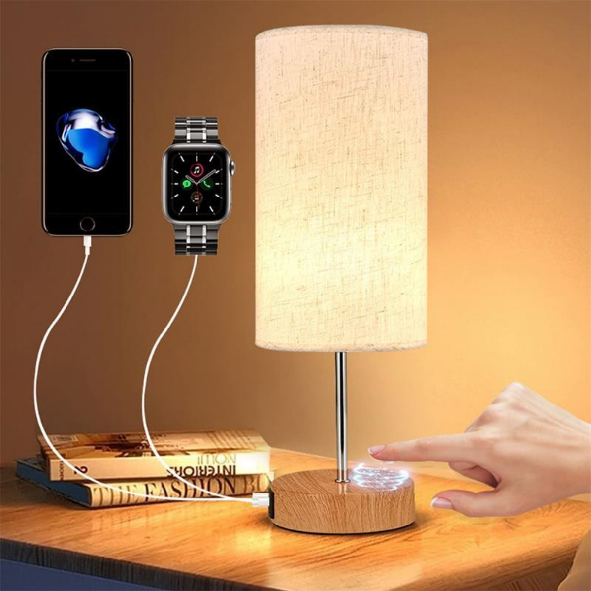 Eine Lampe mit Holzsockel hat ein Telefon und eine Smartwatch angeschlossen. Eine Hand ist in der Nähe.