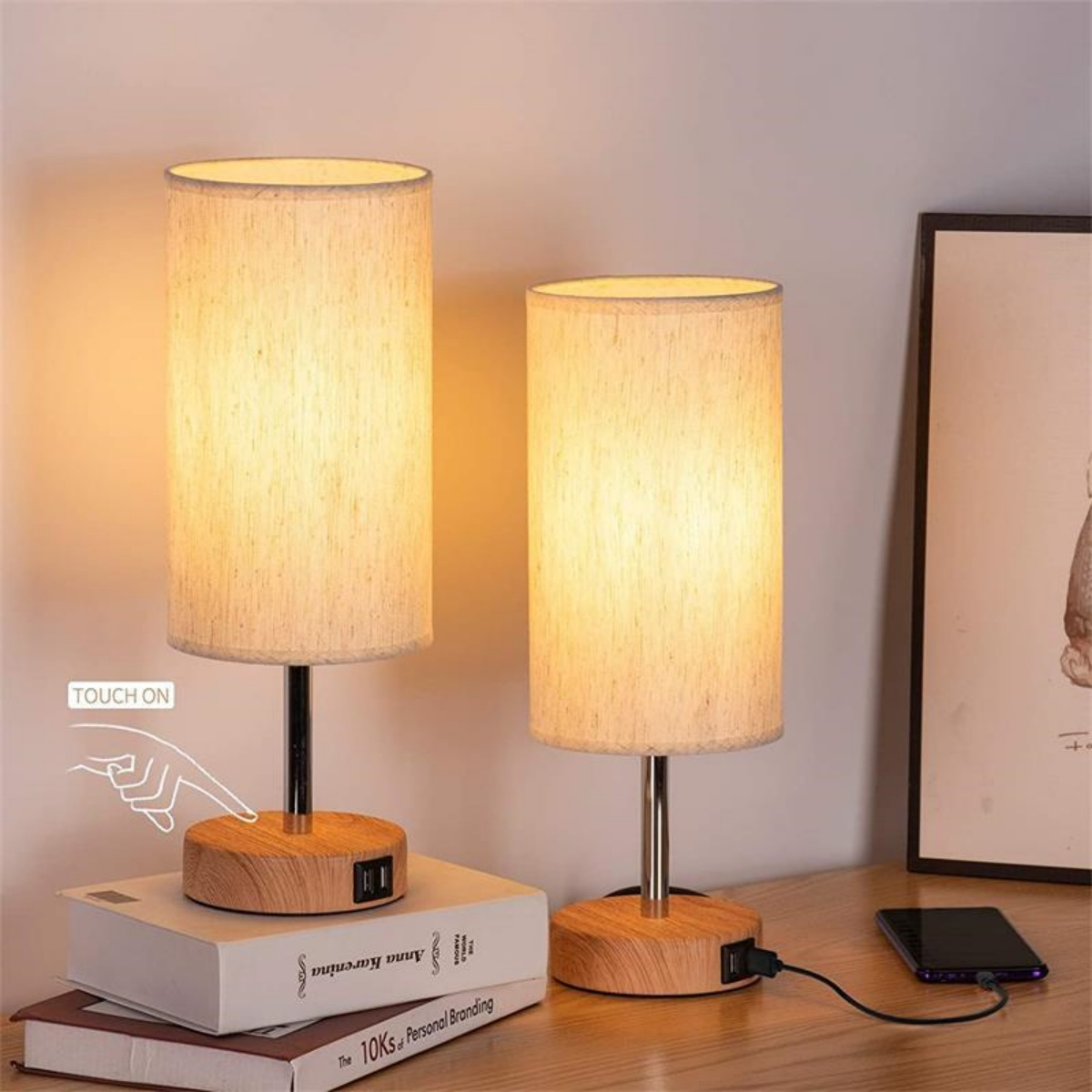Zwei Lampen mit Stoffschirmen auf Holzsockeln. Auf einer steht 'Touch On'. Bücher und ein Telefon in der Nähe.