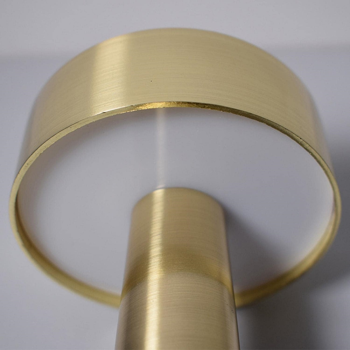 Goldene Lampe mit weißem Diffusor. Die Lampe steht vor weißem Hintergrund.