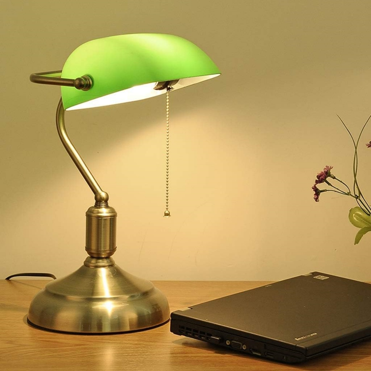 Grüne Schreibtischlampe mit Laptop auf einem Schreibtisch.