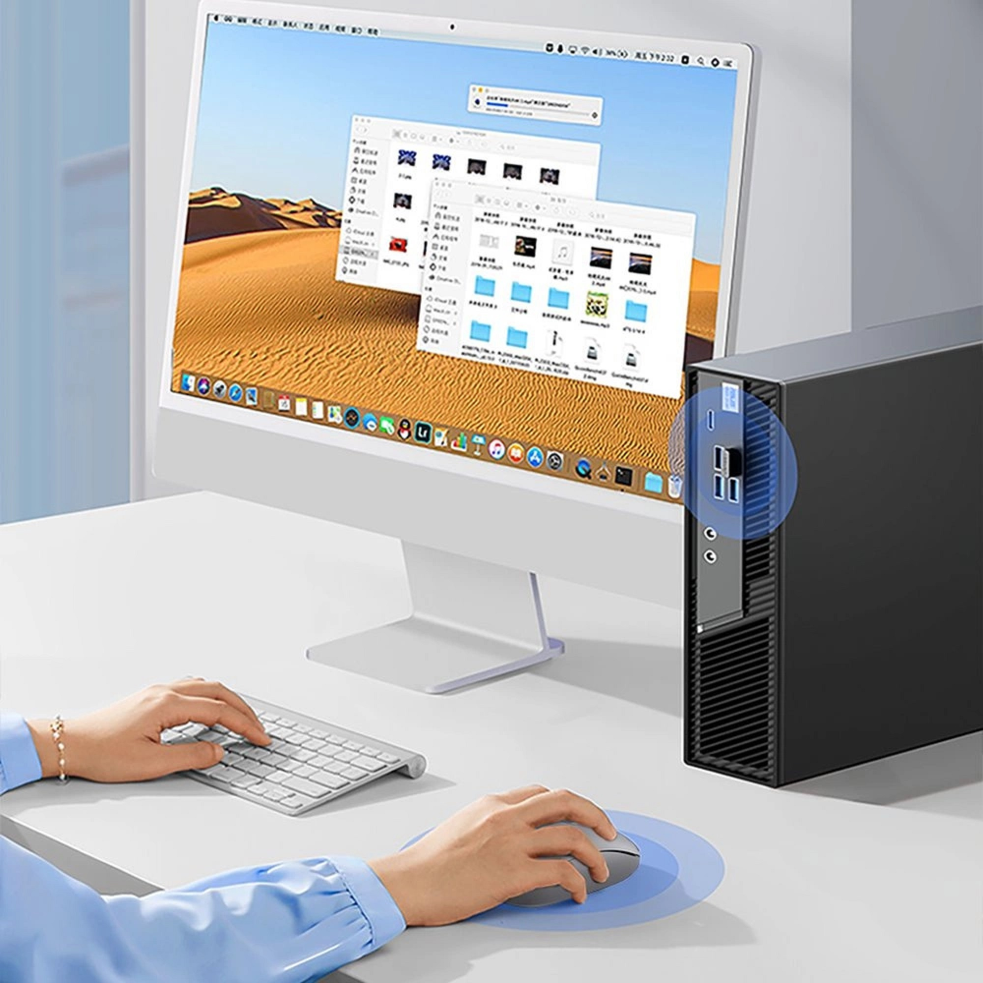 Eine Person benutzt Tastatur und Maus. Computer und Monitor stehen auf dem weißen Schreibtisch.