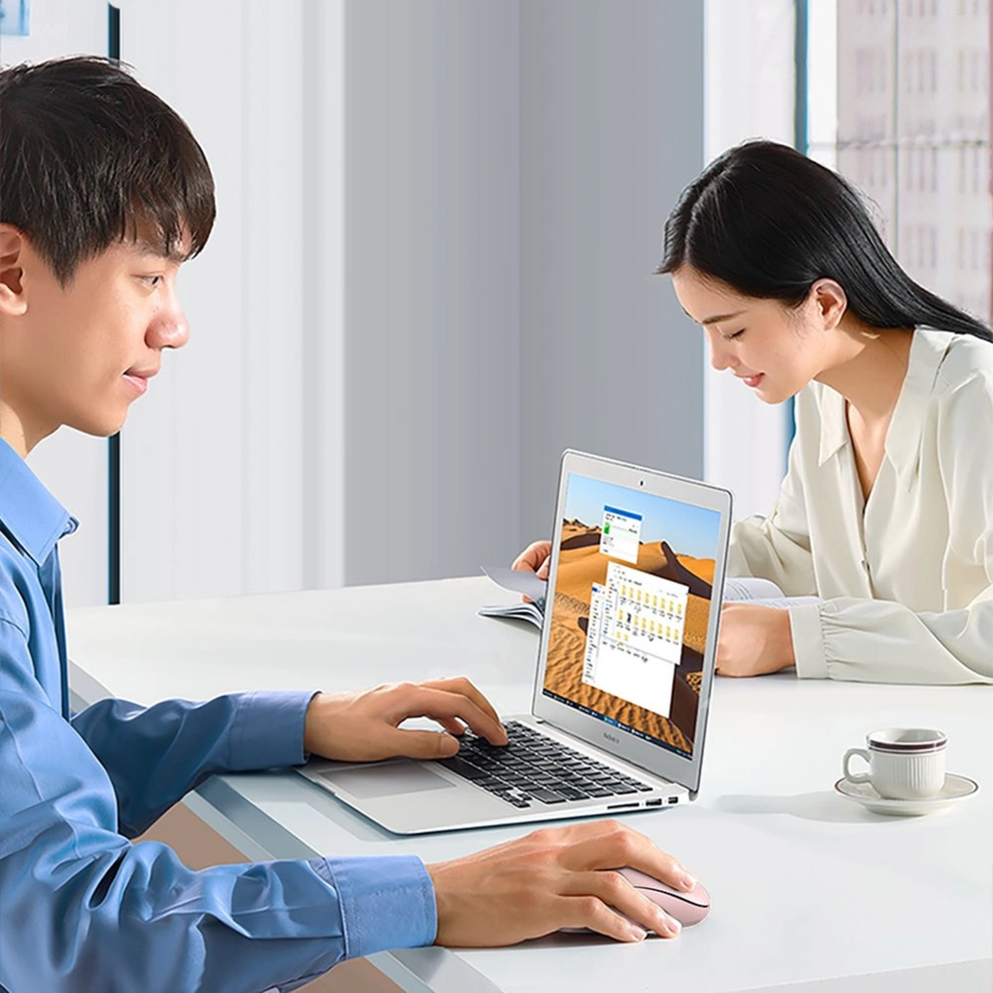Zwei Personen arbeiten an einem Laptop-Computer. Ein Mann tippt, und eine Frau schaut auf den Bildschirm.