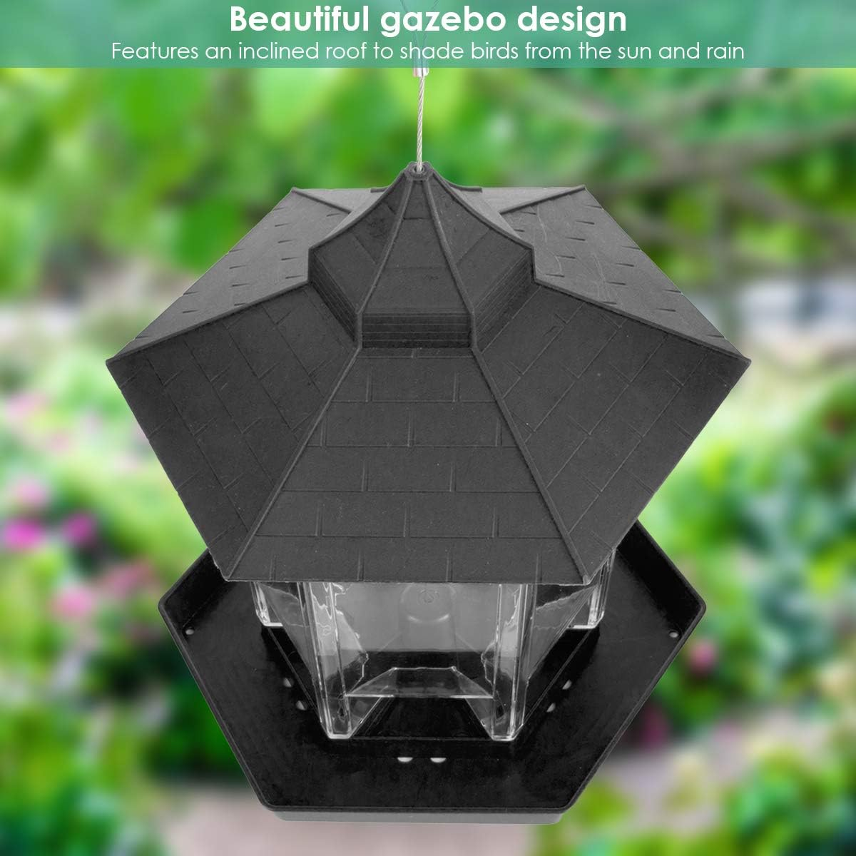Ein schwarzes Vogelfutterhaus mit sechseckigem Dach vor verschwommenem grünem Hintergrund.