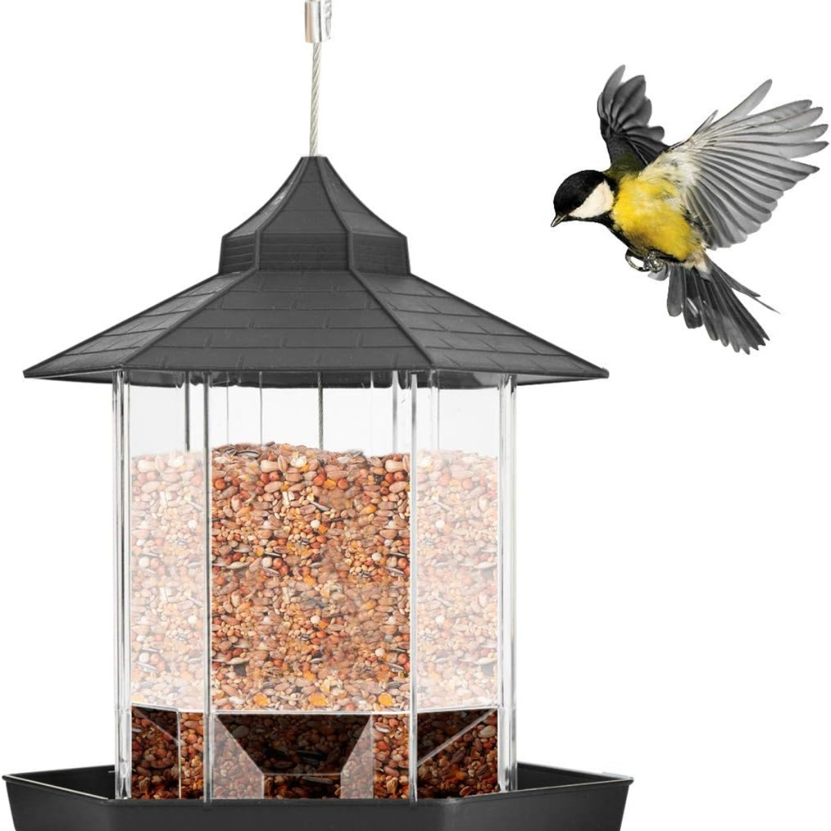 Ein Vogelfutterautomat mit schwarzem Dach und einem Vogel, der darauf zufliegt. Der Automat ist mit Samen gefüllt.