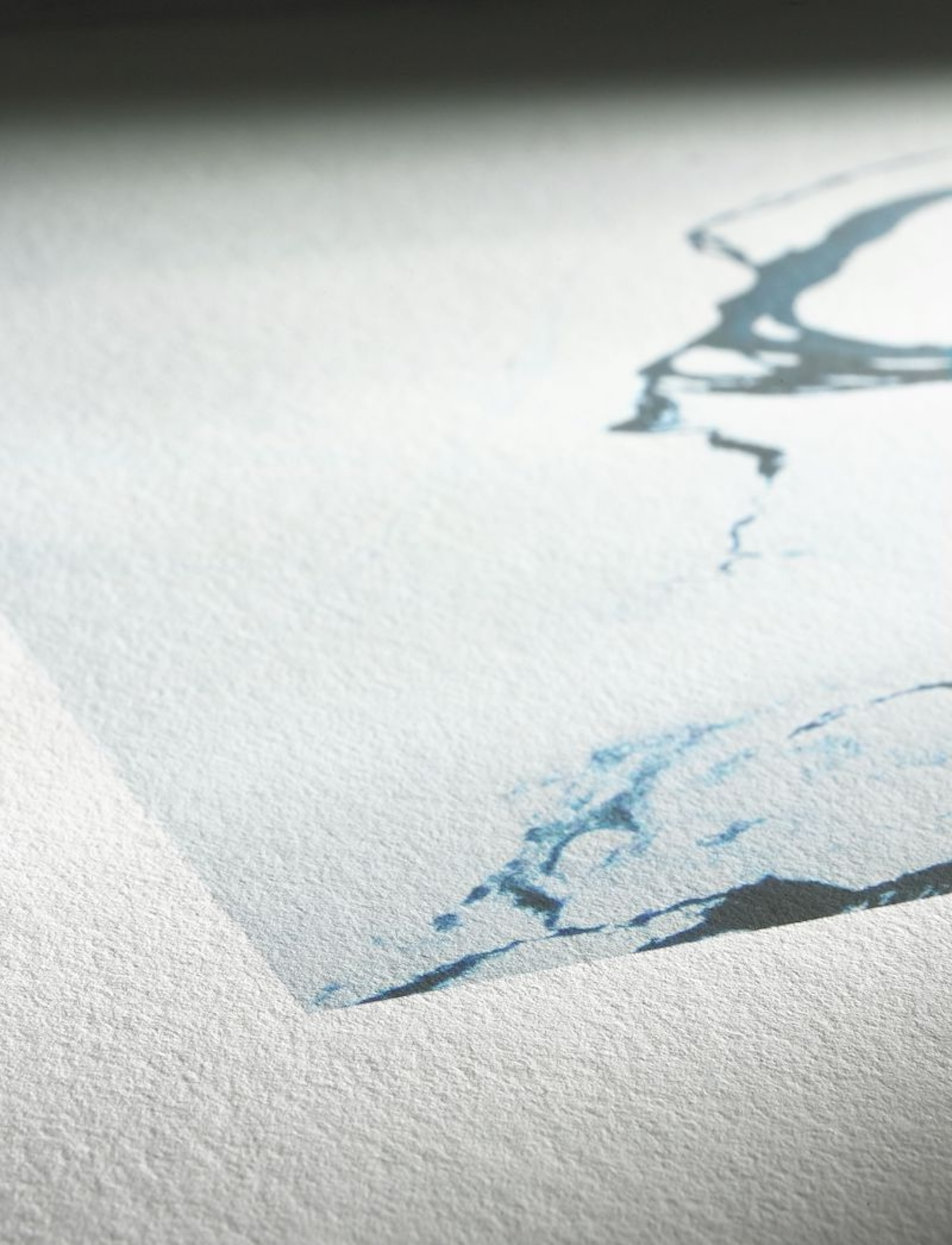 Zbliżenie abstrakcyjnego obrazu akwarelowego na papierze, z niebieskim tuszem i białym obramowaniem.