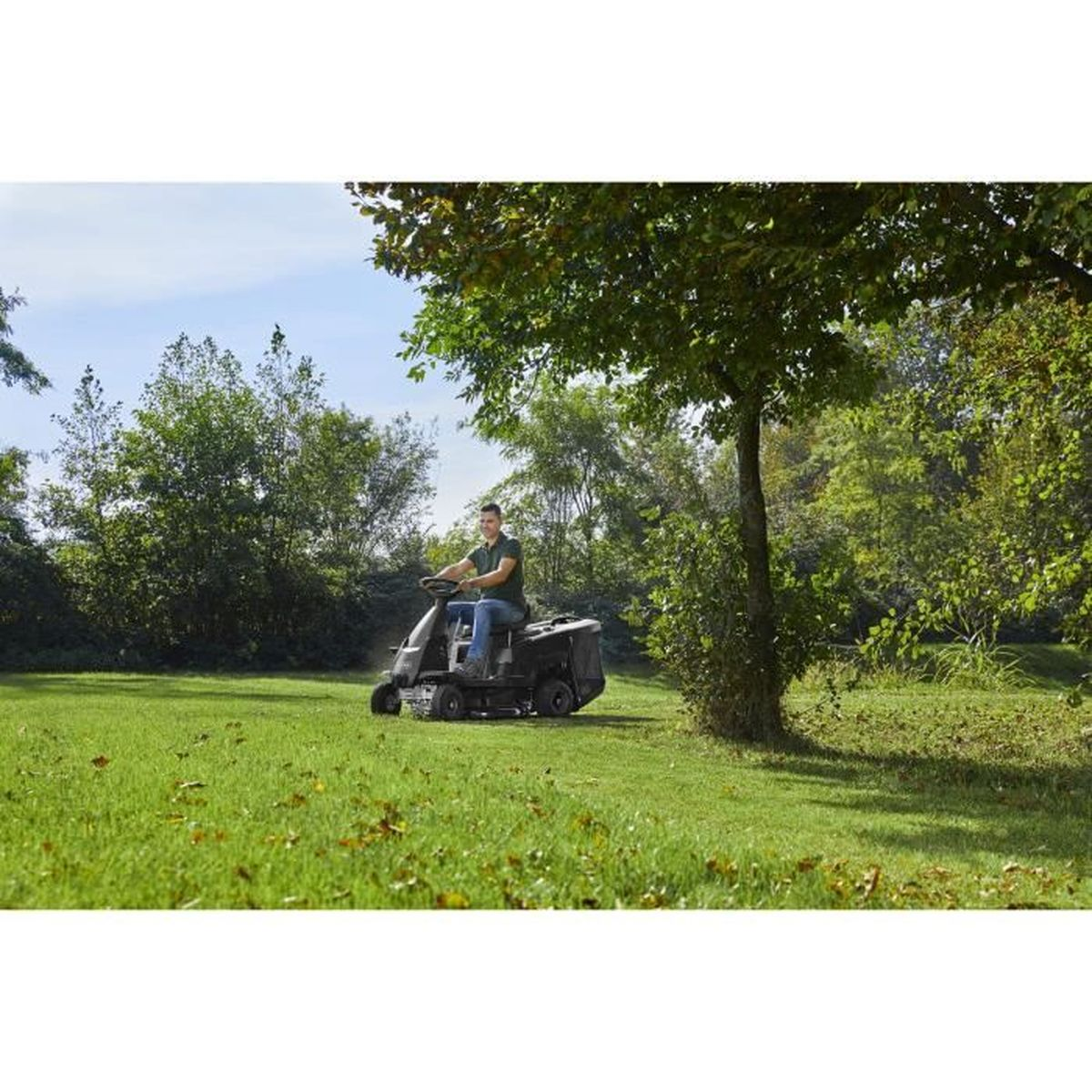 Eine Person mäht den Rasen mit einem Aufsitzmäher auf einer grünen Wiese.