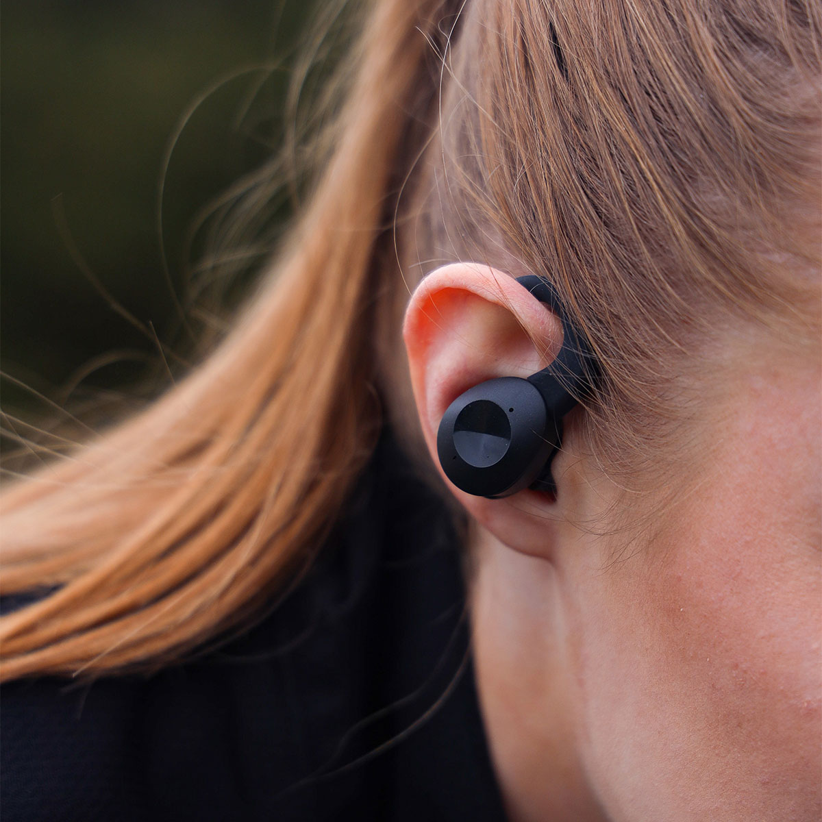 Donna con auricolare nero nell'orecchio, primo piano dell'orecchio e dell'auricolare.