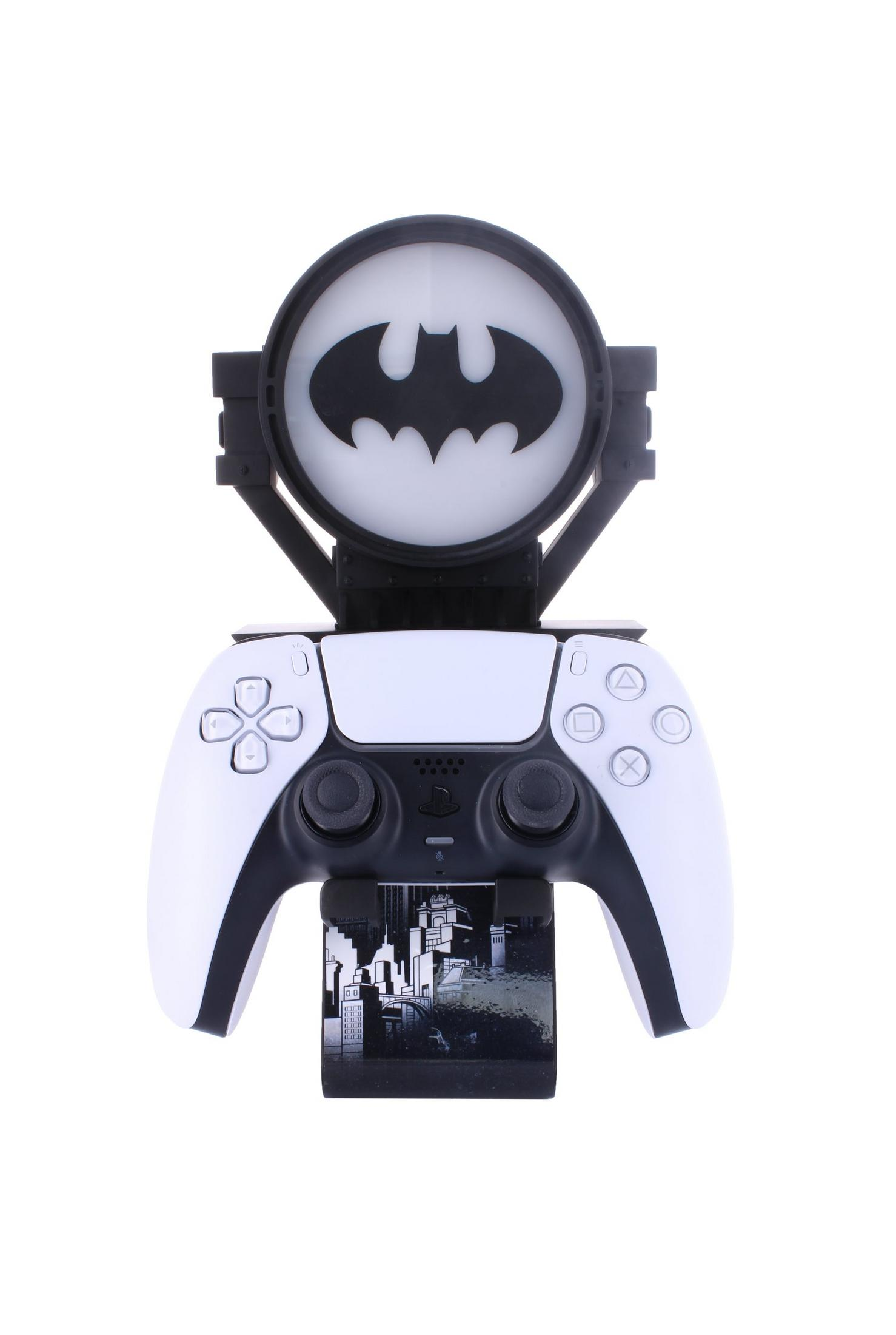 Controller PS5 bianco con supporto simbolo Batman, e un'immagine di paesaggio urbano.