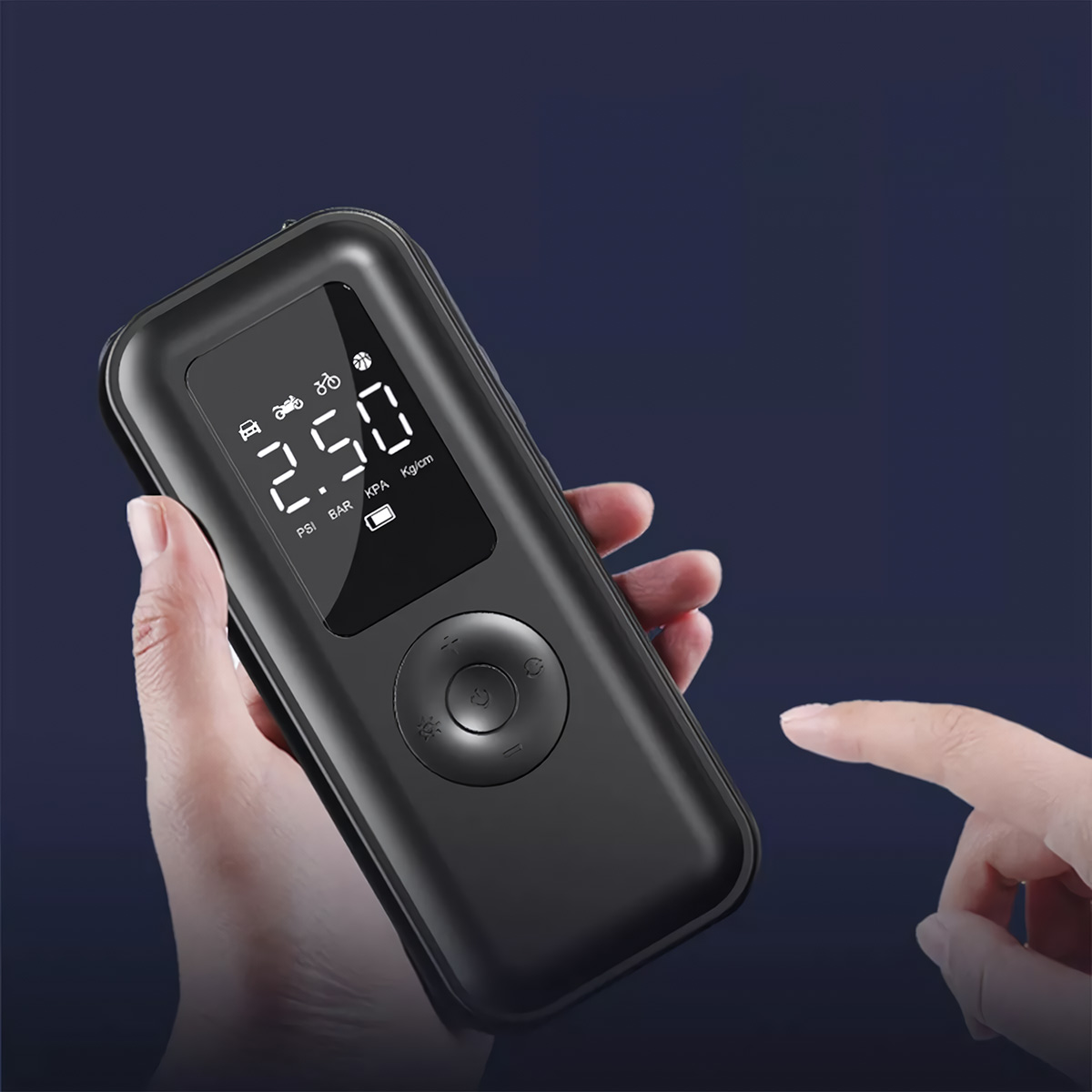 Una mano sosteniendo un inflador de neumáticos digital negro contra un fondo azul oscuro.