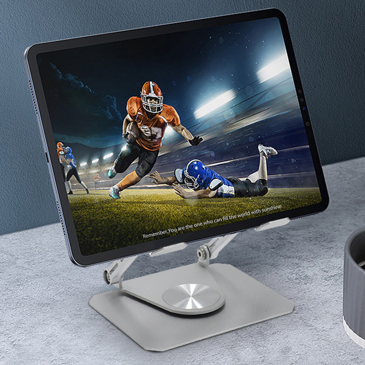 Ein Tablet mit einem Footballspiel auf einem silbernen Ständer. Zwei Spieler liegen am Boden.