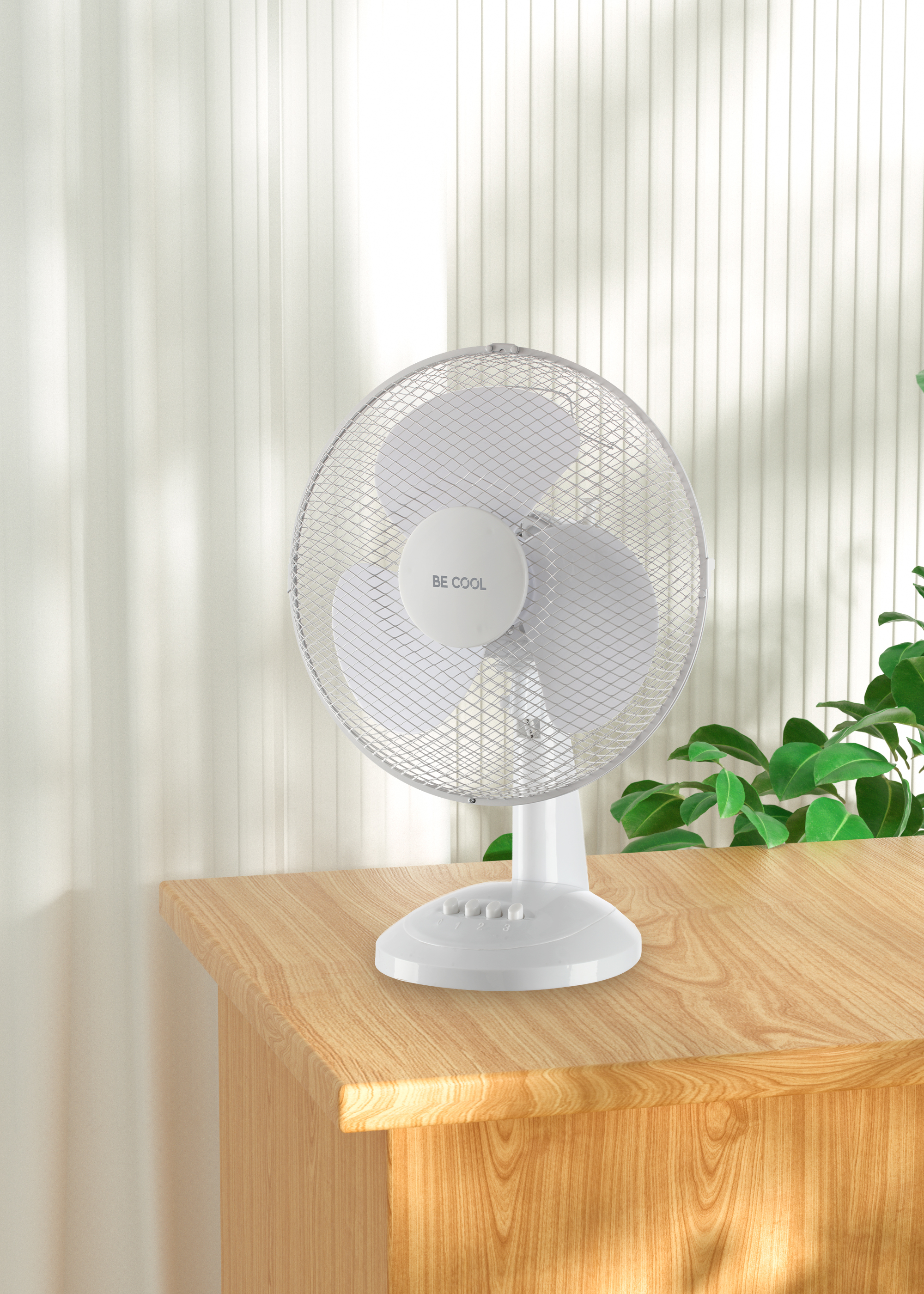 Weißer Tischventilator auf einem Holztisch mit grünen Pflanzen. Der Ventilator hat ein weißes Gitter und einen Sockel.