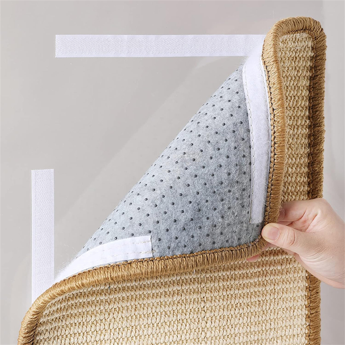 Beige gewebte Matte mit grauer Unterseite, mit Klettverschluss an der Wand befestigt. Eine Hand schält eine Ecke ab.