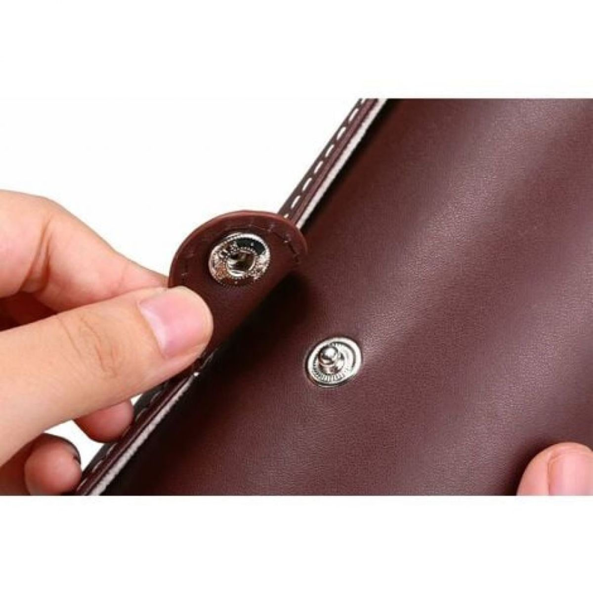 Eine braune Lederbrieftasche, wobei eine Hand einen Schnappverschluss öffnet.