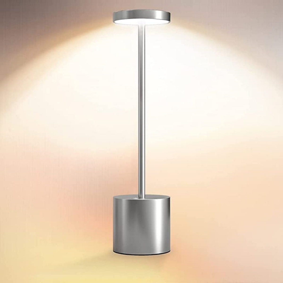 Eine silberne, zylindrische LED-Lampe mit rundem Kopf leuchtet vor einer orangefarbenen Wand.