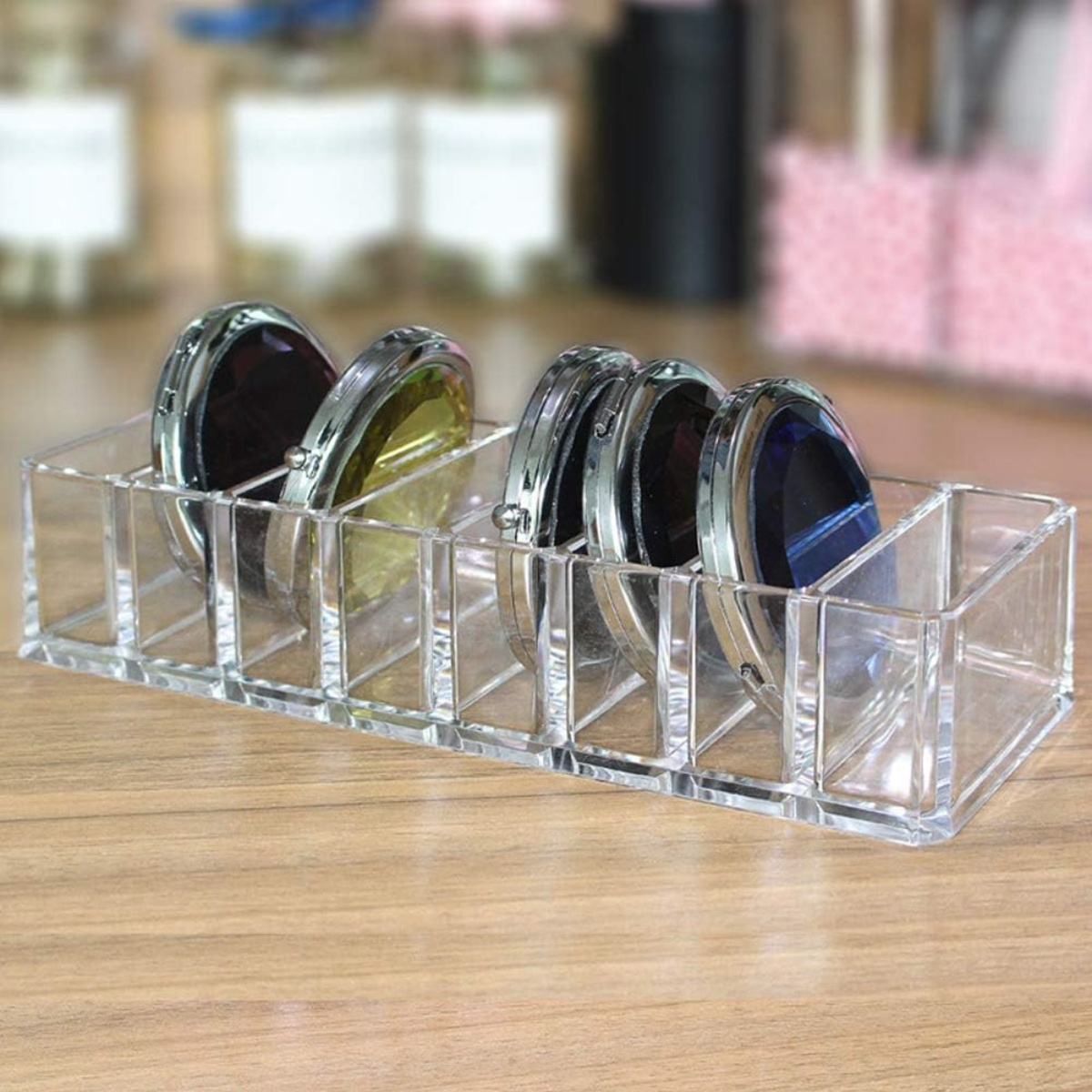 Transparenter Make-up-Organizer aus Acryl mit verschiedenen Make-up-Artikeln, auf Holz.