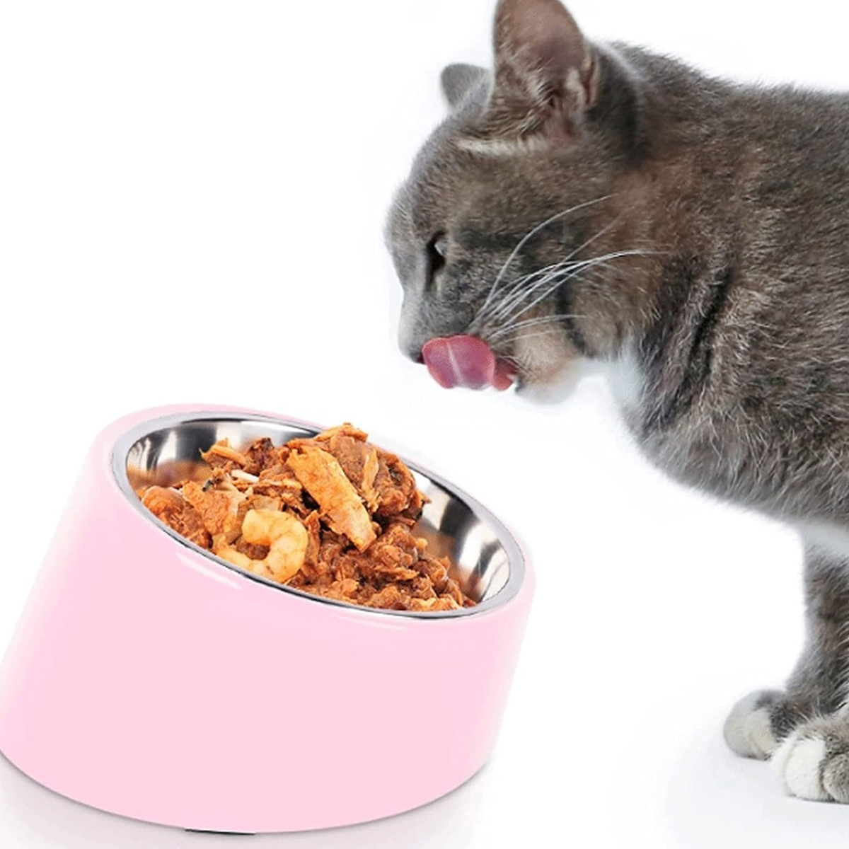Eine Katze leckt ihre Lippen in der Nähe einer rosa, geneigten Futterschüssel, gefüllt mit Futter.