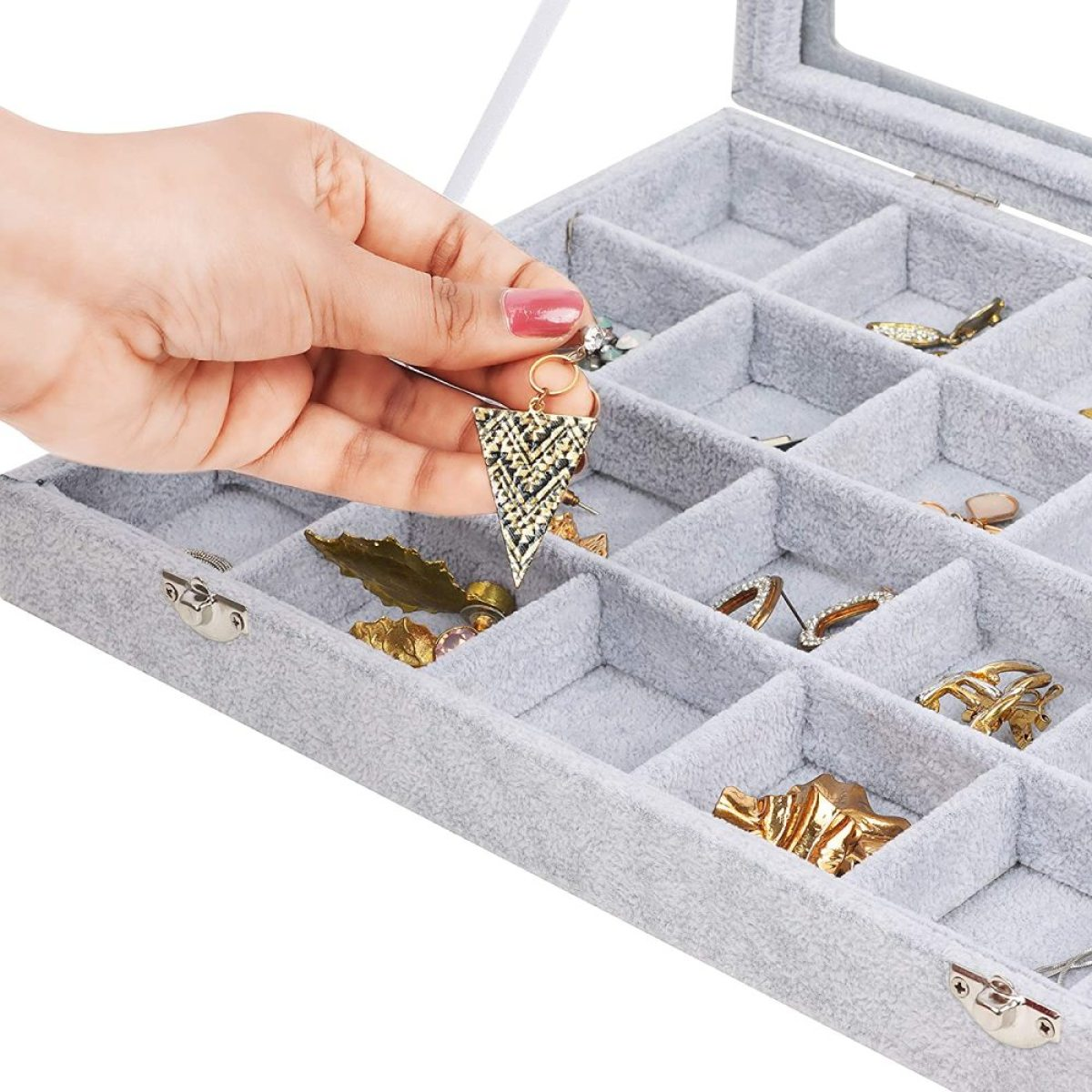 Eine Hand wählt einen goldenen Ohrring aus einer grauen Schmuckschatulle aus.
