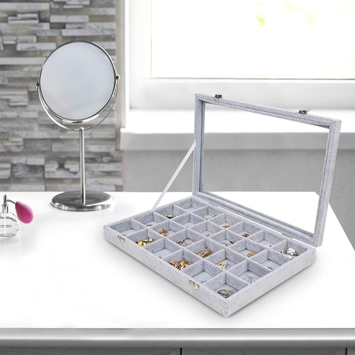 Ein Schmuck-Display-Case mit Glasdeckel. Die Case ist geöffnet und mit Schmuck gefüllt. Weißer Tisch.