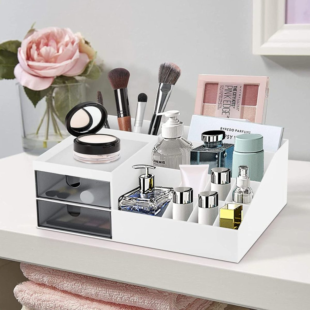 Weißer Kosmetik-Organizer mit Make-up-Artikeln auf weißer Oberfläche mit Schubladen.