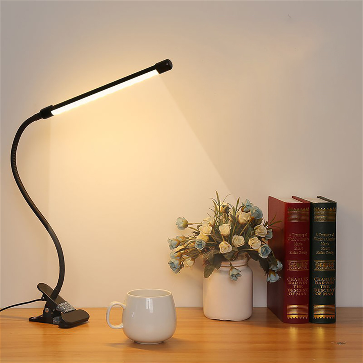 Schreibtischlampe mit flexiblem Hals und weißem Becher. Bücher und Blumen auf dem Schreibtisch.