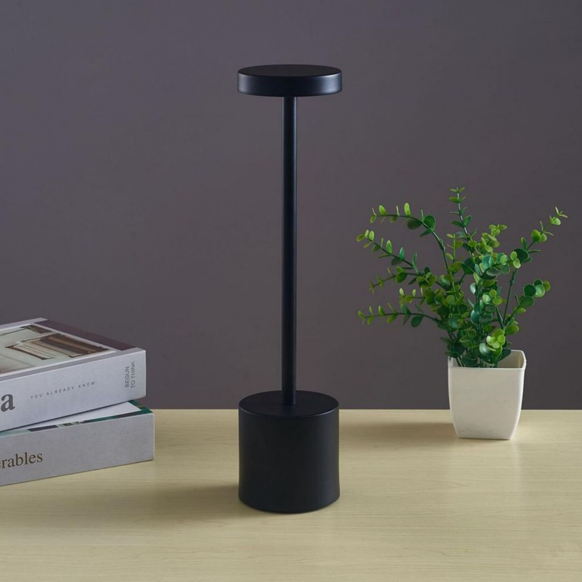 Schwarze Lampe mit rundem Ober- und Unterteil, schlankem Stiel und weißem Hintergrund.