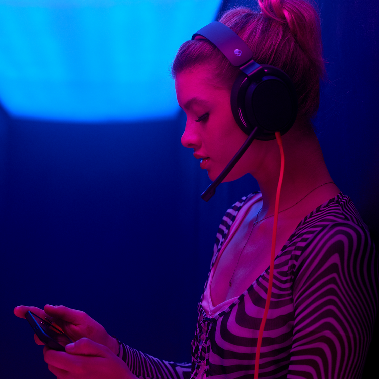 Kobieta w słuchawkach grająca w grę, niebieskie i czerwone światło.