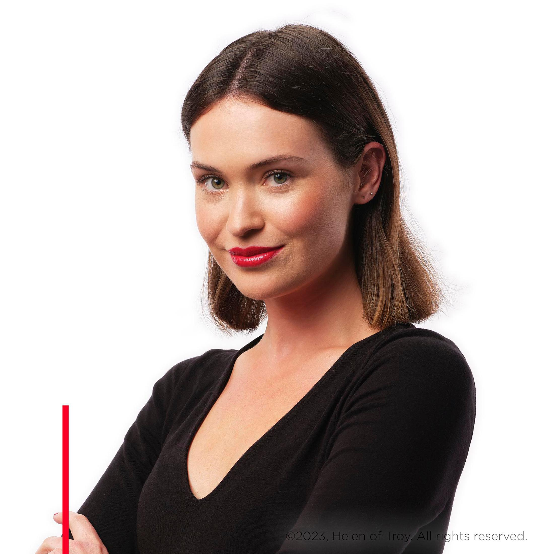Una donna con capelli castani corti, rossetto rosso e un top nero. Braccia incrociate.