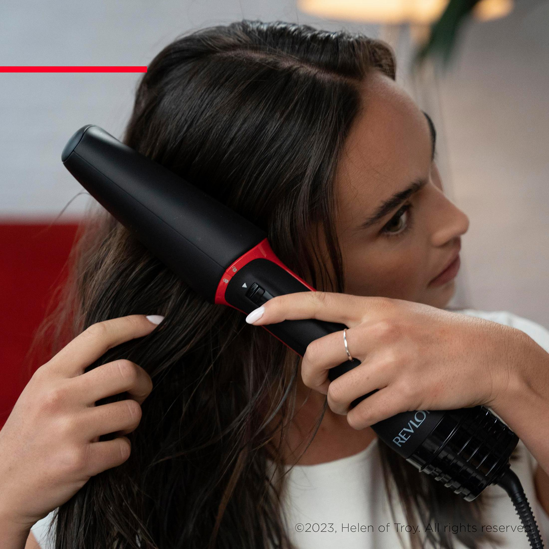 Donna che usa una spazzola per capelli Revlon nera e rossa sui suoi capelli.