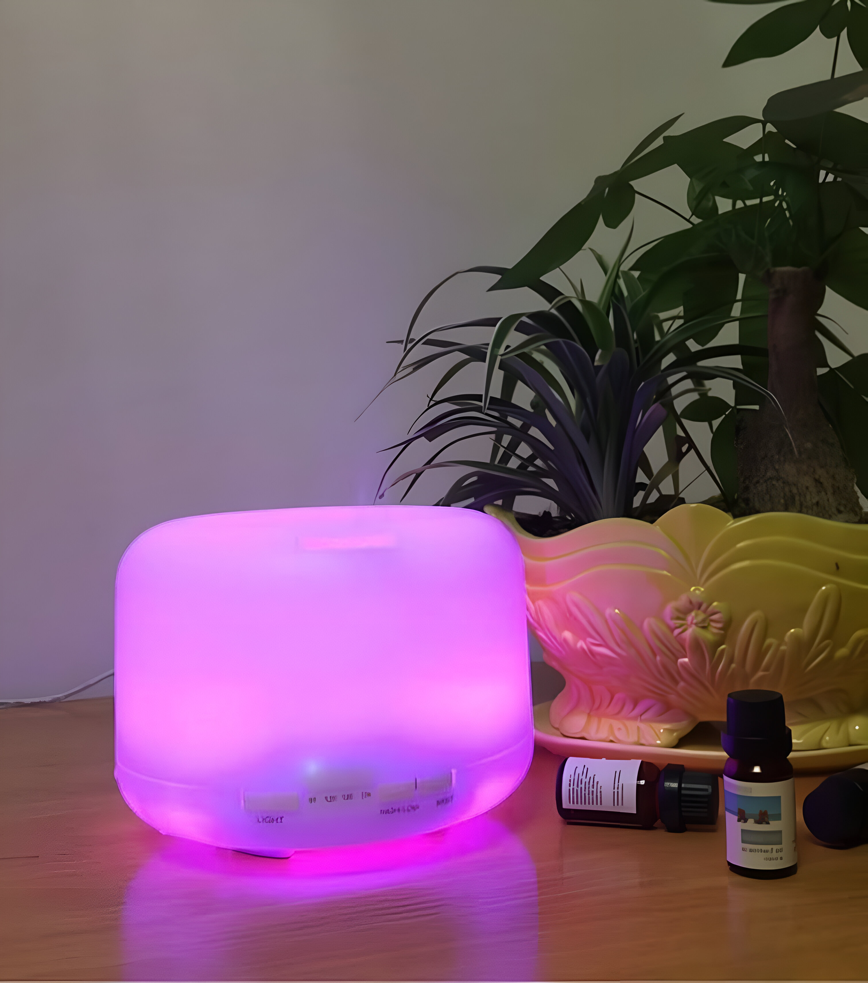 Un humidificador blanco y rosa brilla, con aceites esenciales y una planta en el fondo.
