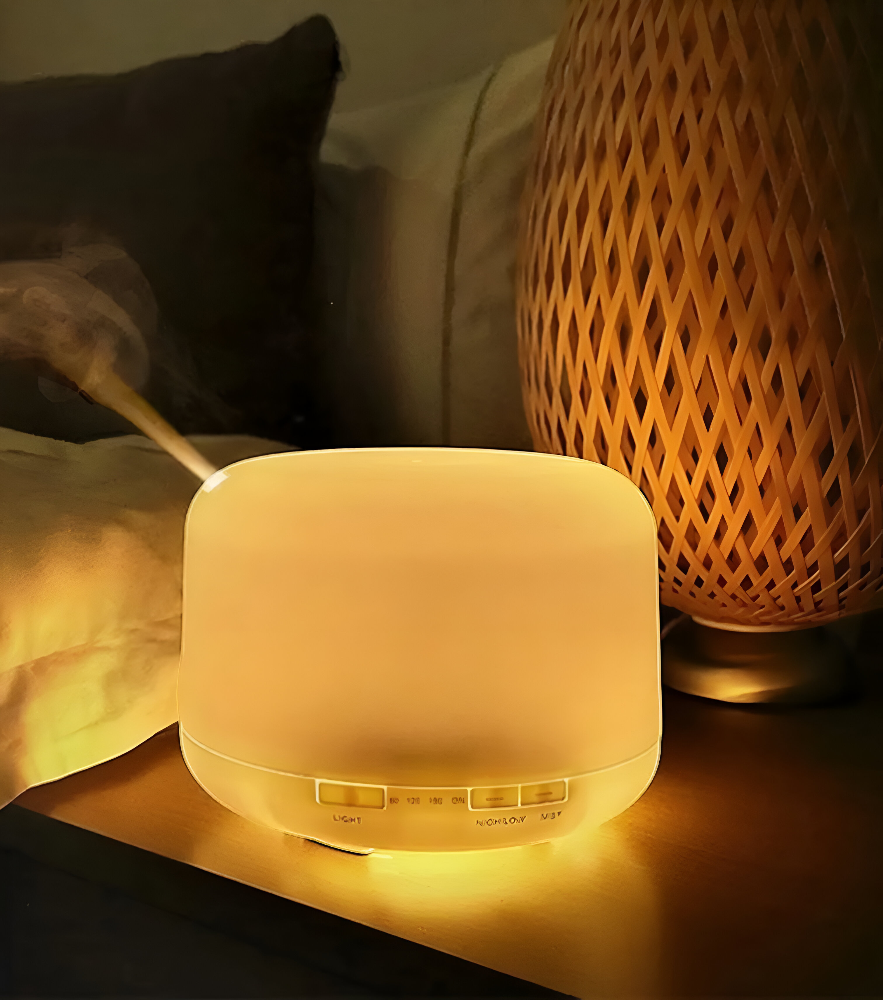 Un humidificador blanco iluminado sobre una superficie de madera, con una lámpara tejida al fondo. Escena tenue.